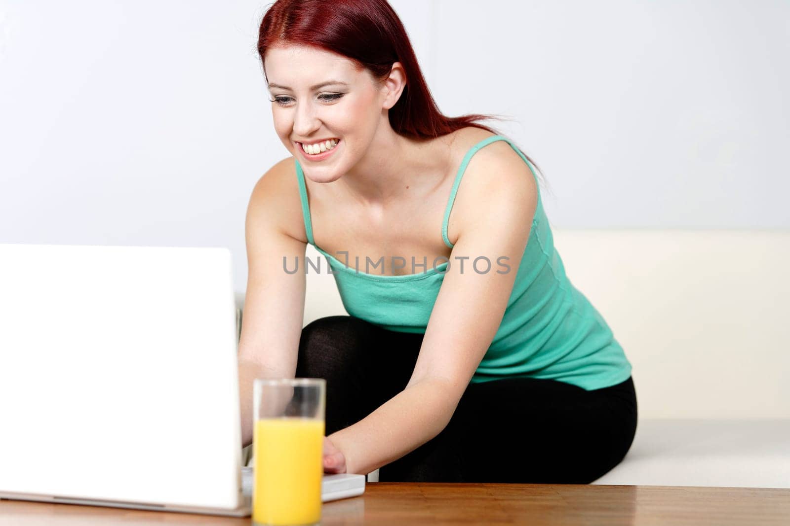 Happy smiling woman chatting with friends on a laptop at home on the sofa