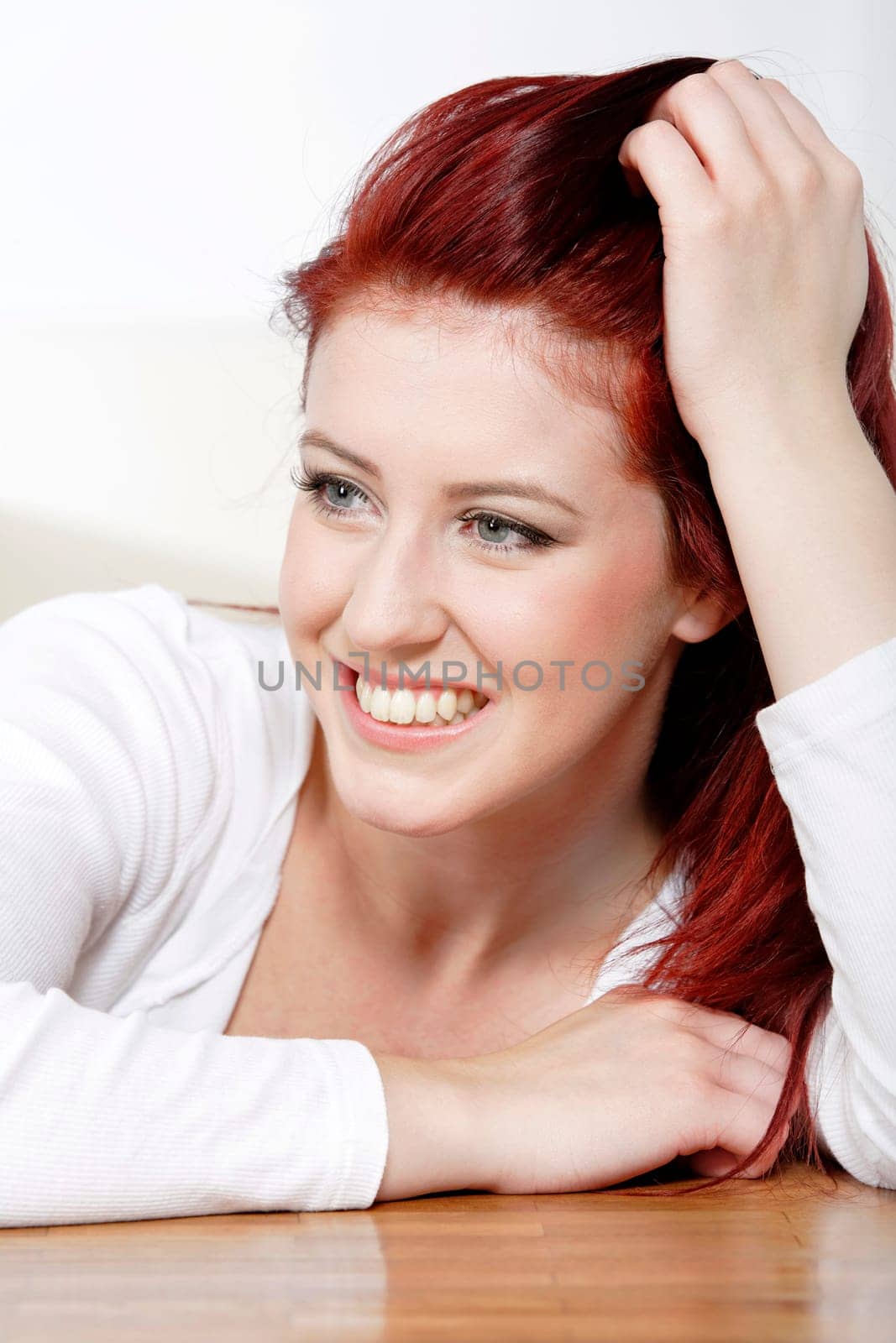 Beautiful young woman resting on a coffee table in front of sofa at home.