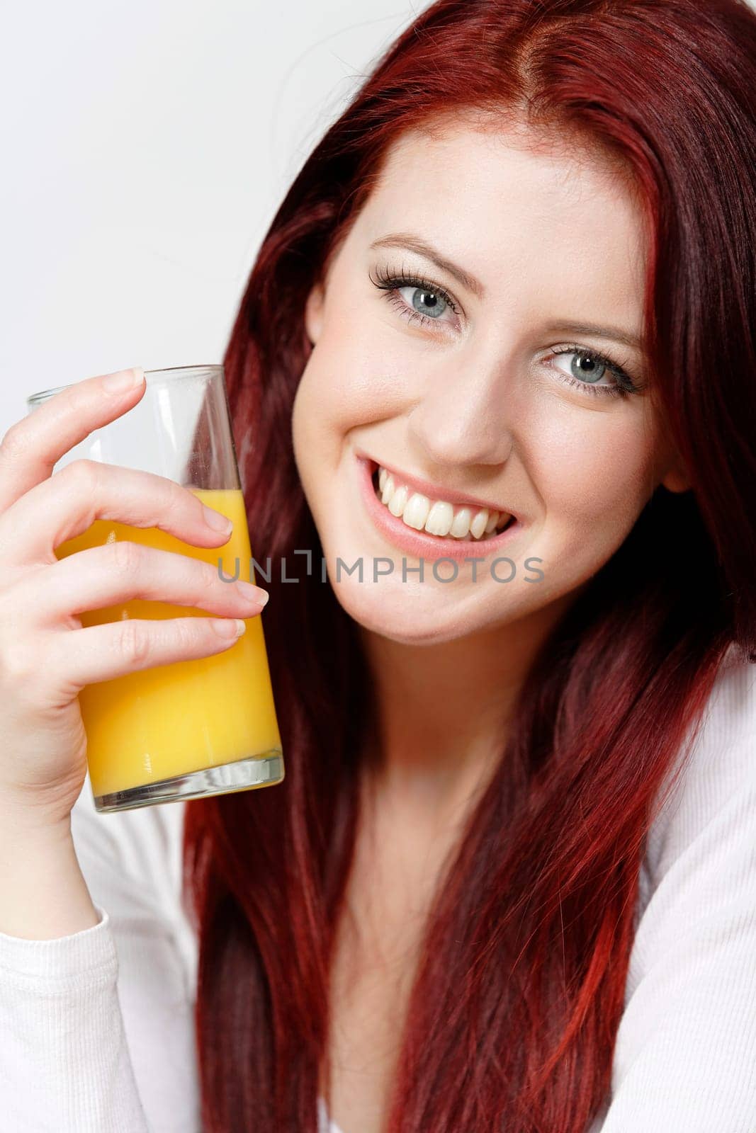 Smiling happy young woman with a fresh glass of Orange juice during breakfast.