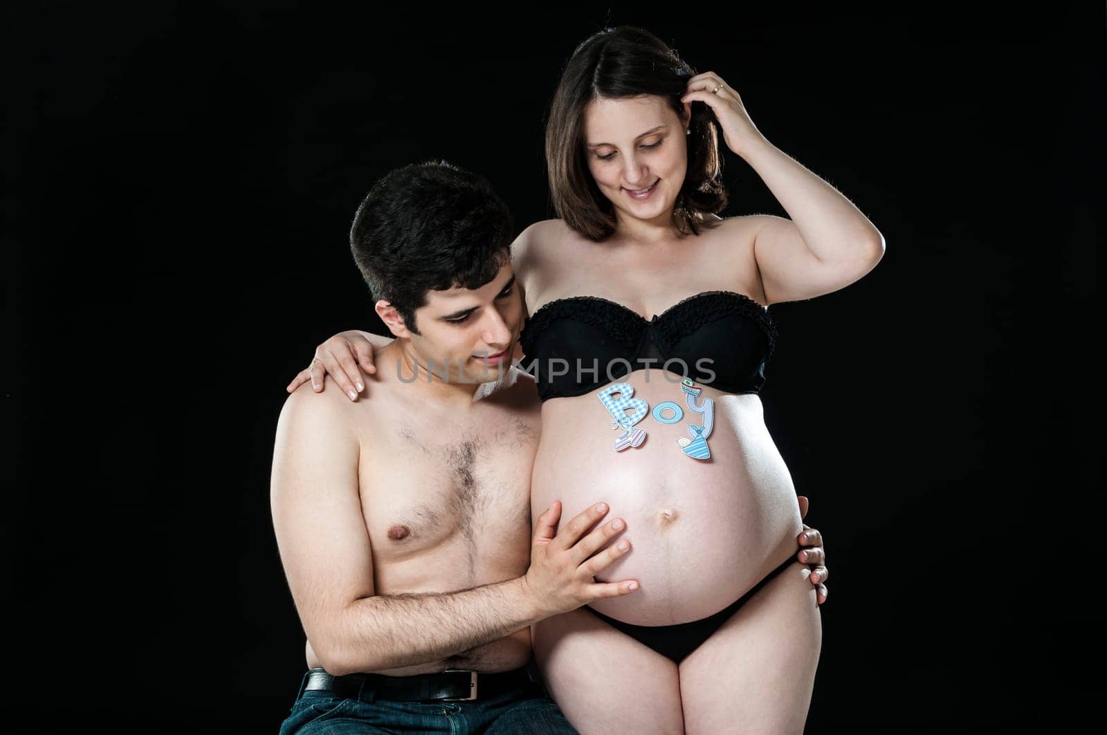 Portrait of young couple looking at baby belly and smiling