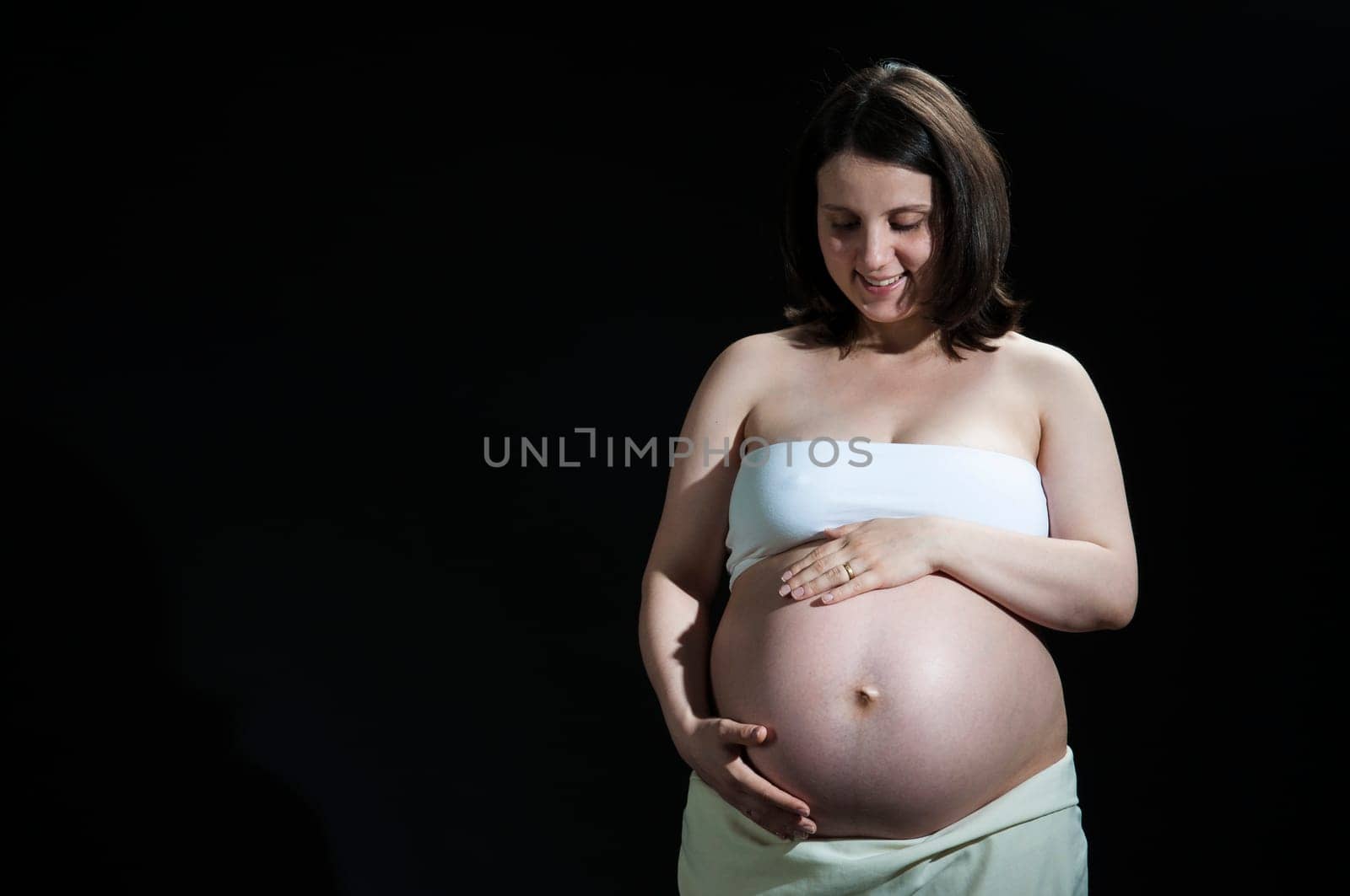 Portrait of happy young pregnant woman feeling her baby belly.