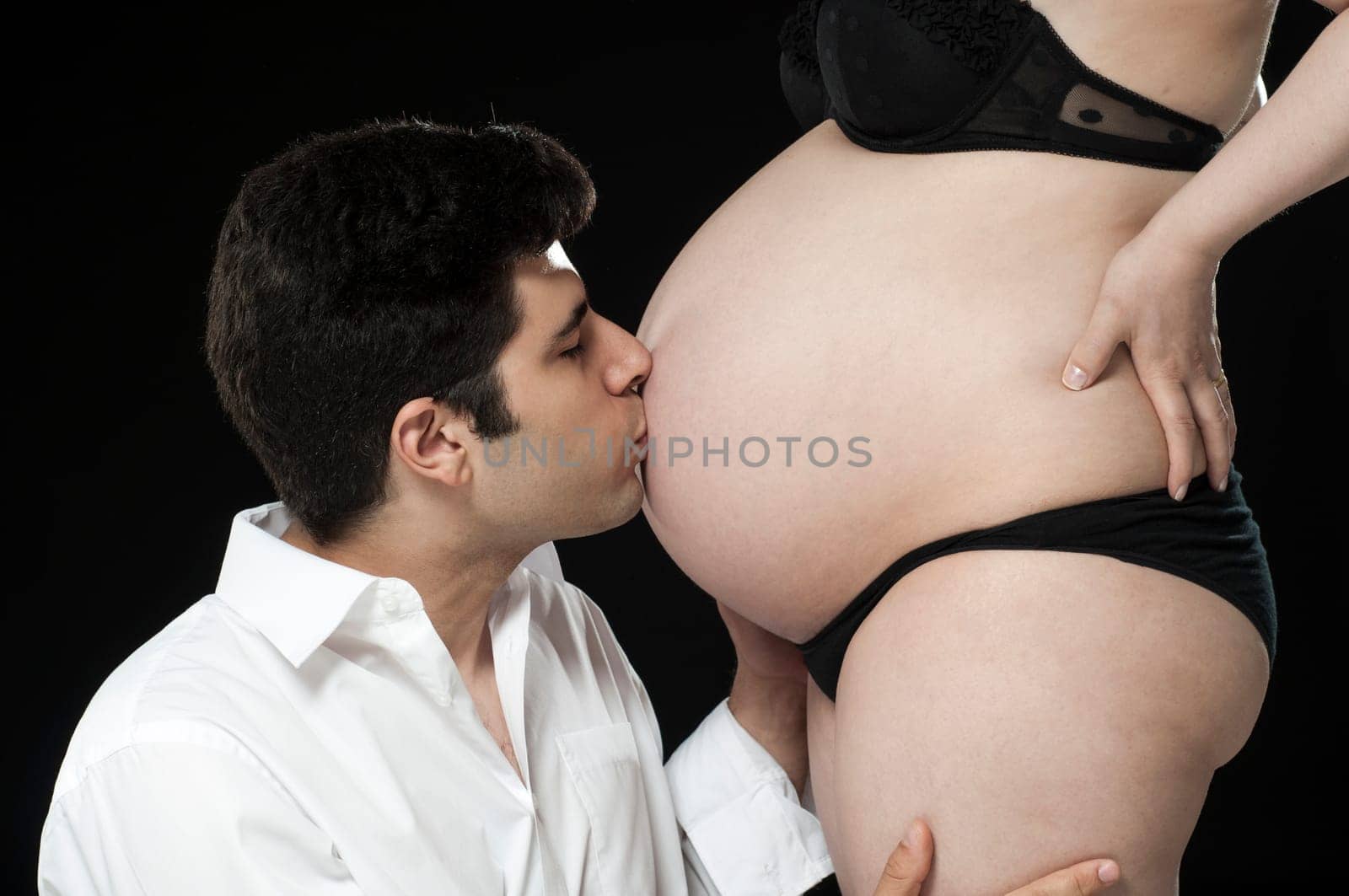 Portrait of young father kissing baby belly.