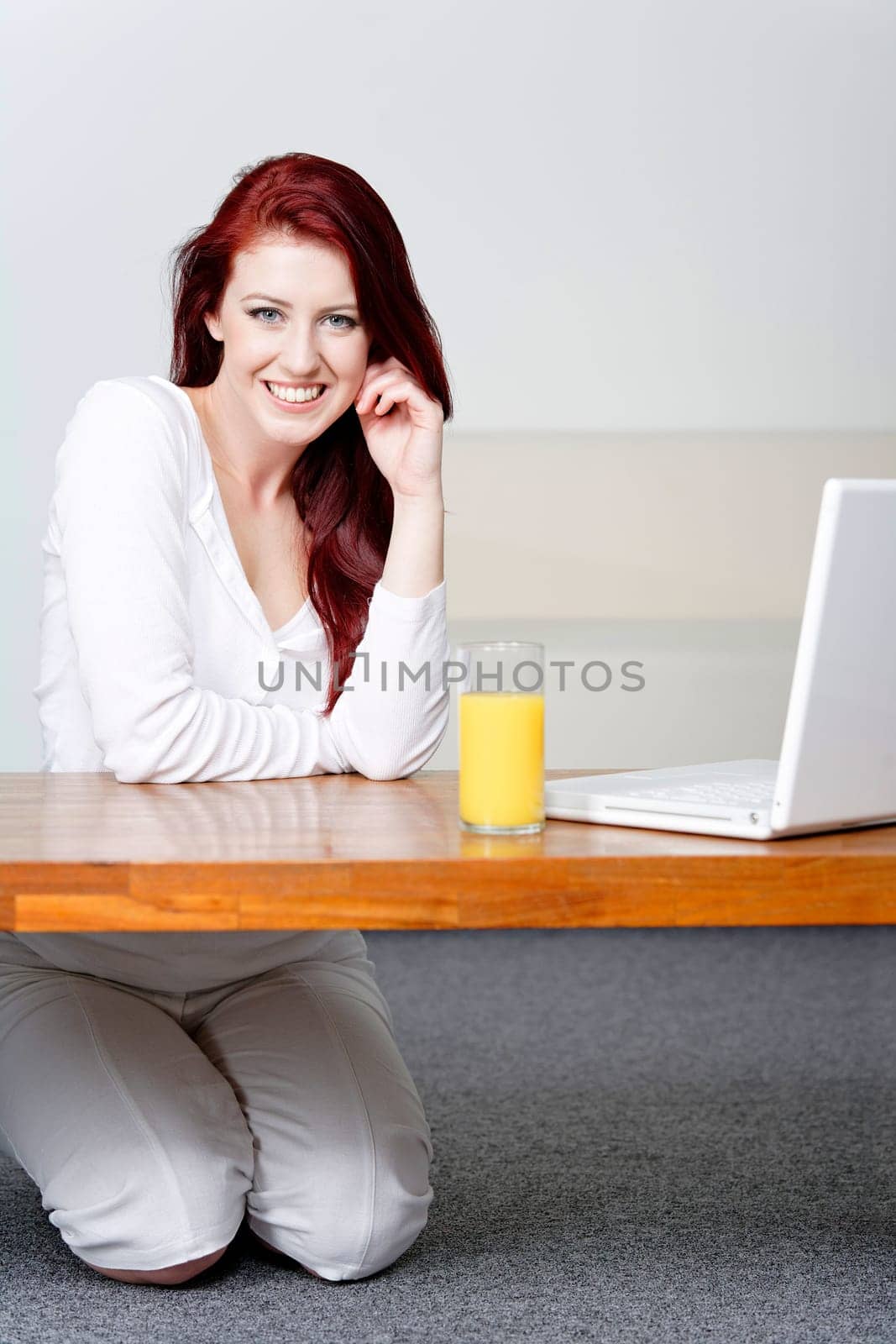 Beautiful young woman using a laptop at home with a fresh glass of Orange juice.