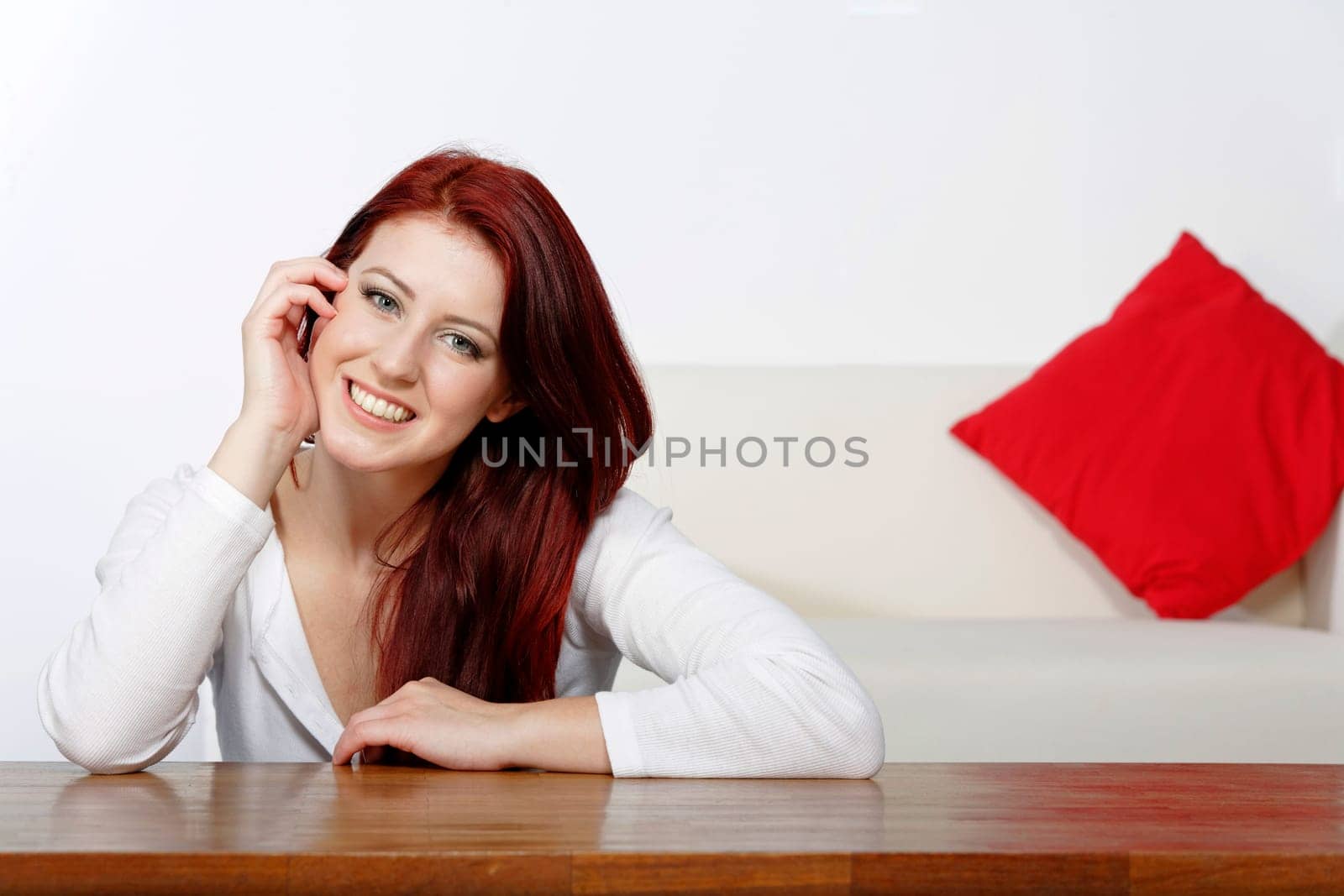Beautiful young woman resting on a coffee table in front of sofa at home.
