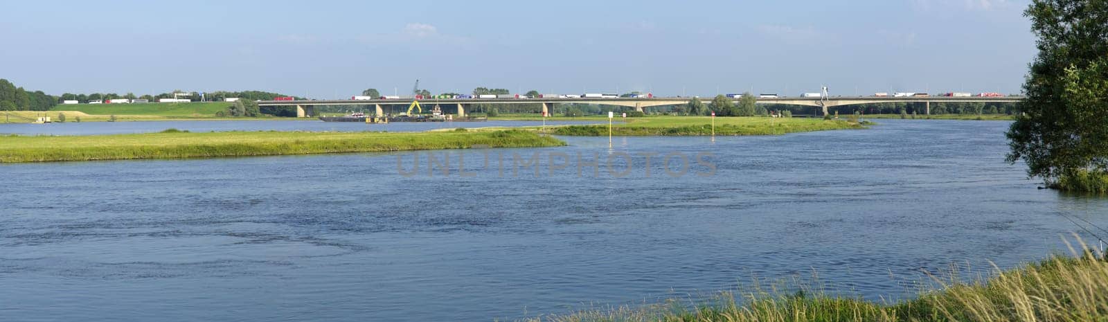 panoramic view of the IJssel river at Deventer in the Netherlands. In the background a large highway bridge with traffic