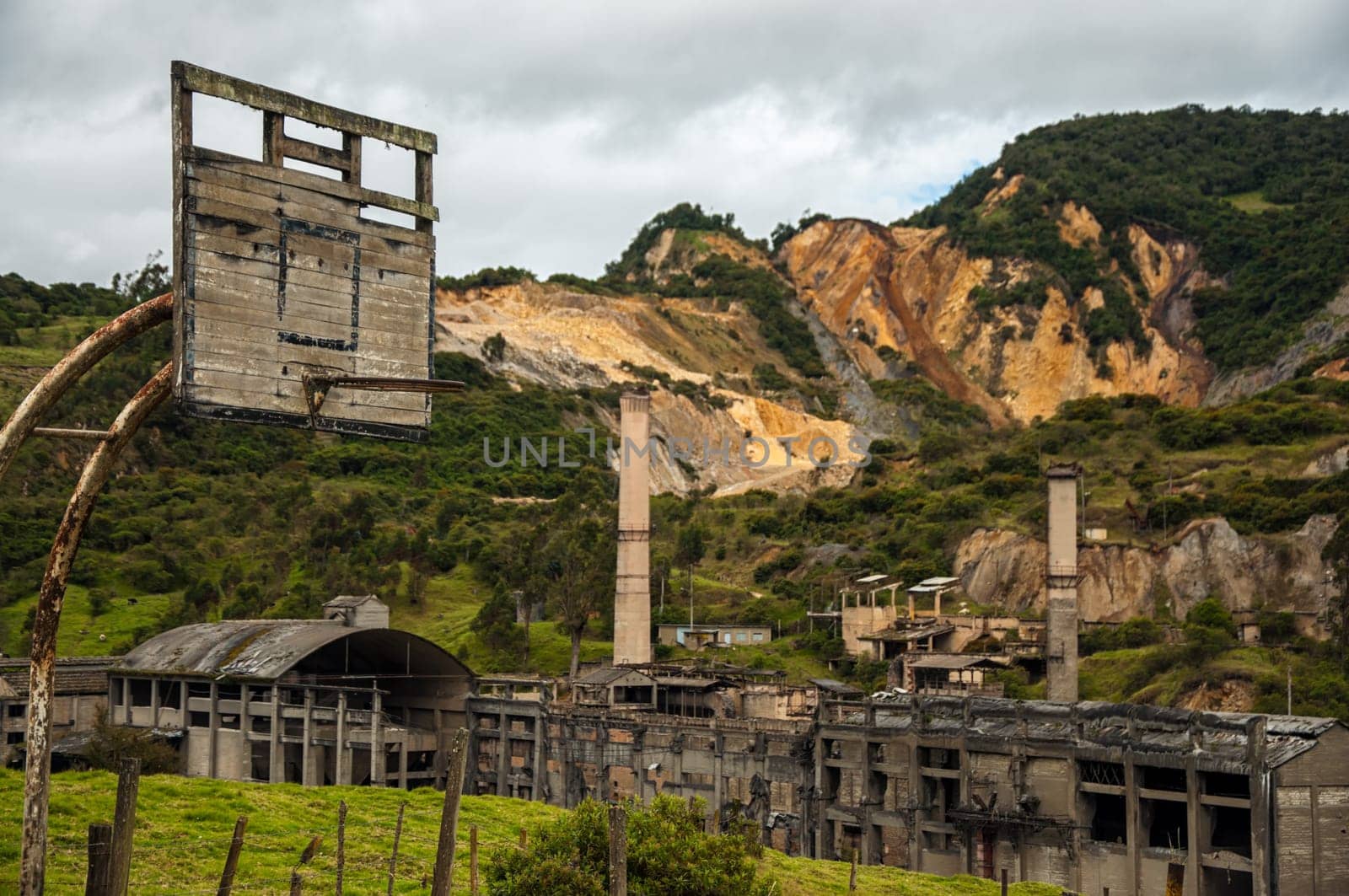 An old basketball hoop with a destroyed factory in the background.