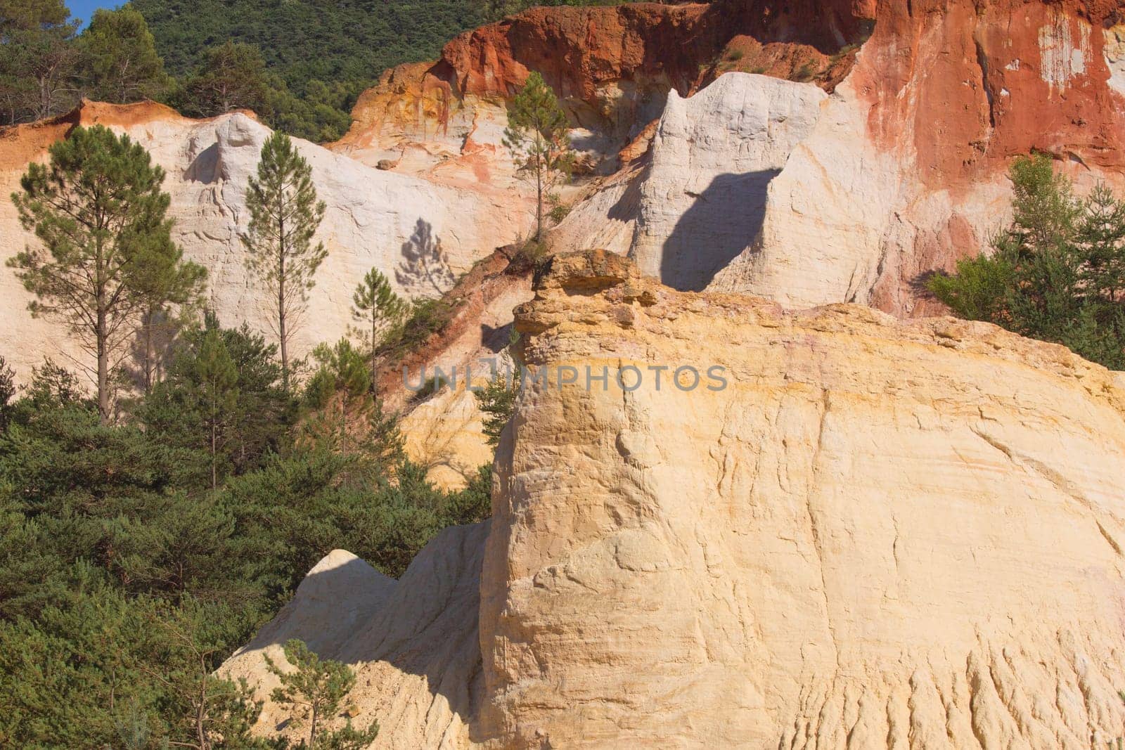 White and red ocher hills and blue sky in the background. Ocher rocks (French Colorado) near Rustrel (Provence, Southern France)