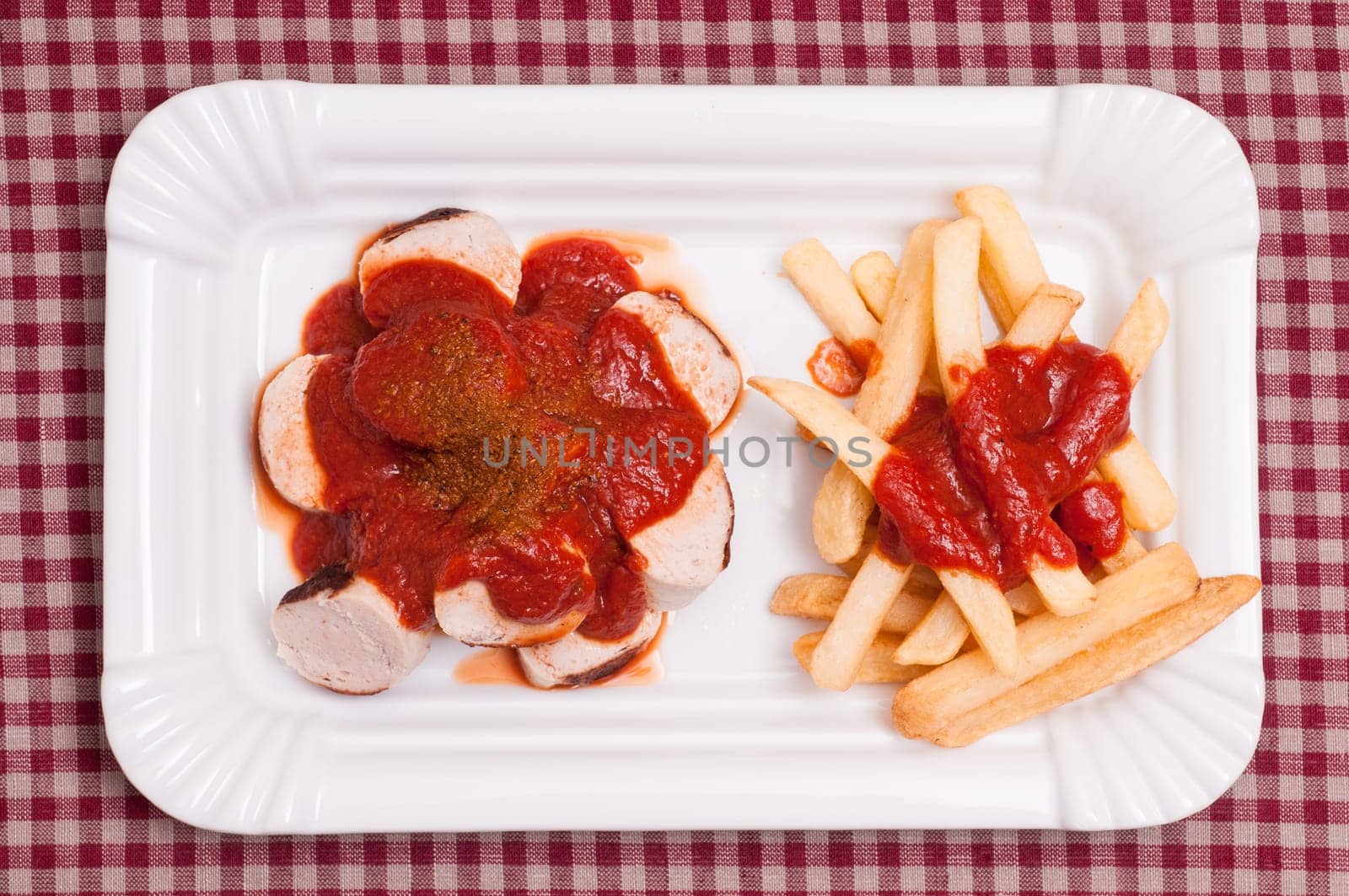 Currywurst with French fries in a white bowl