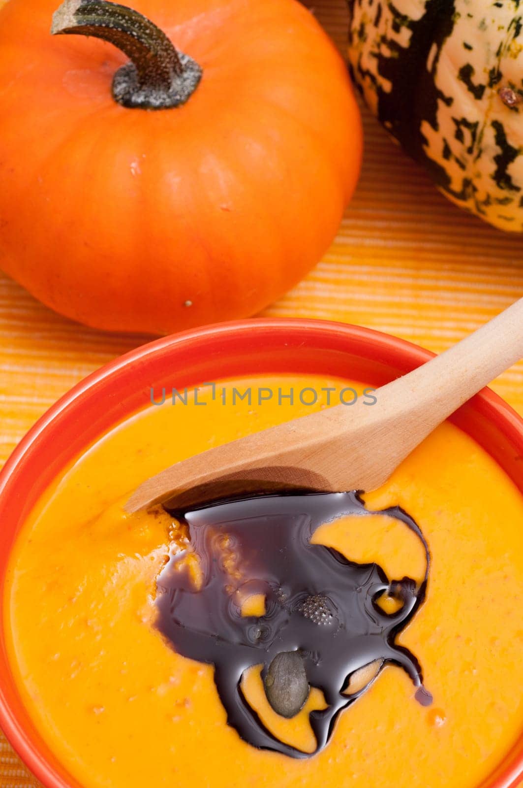 Pumpkin soup with pumpkin seed oil and wooden spoon