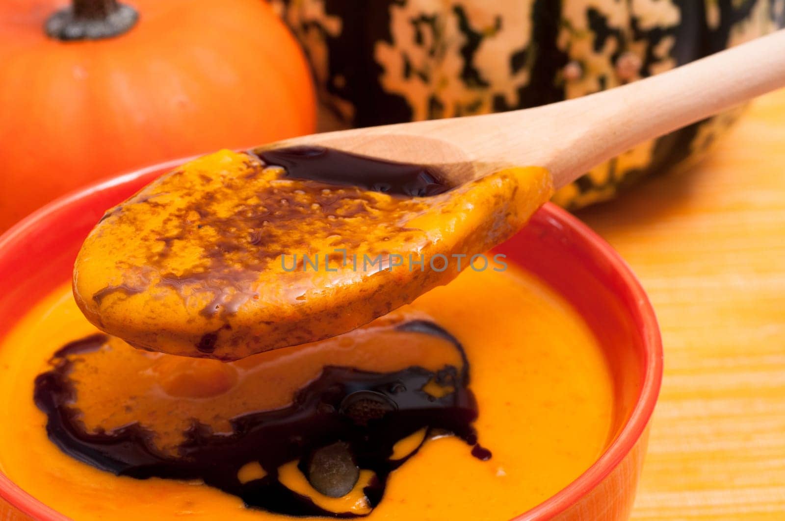 Pumpkin soup with pumpkin seed oil on a wooden spoon