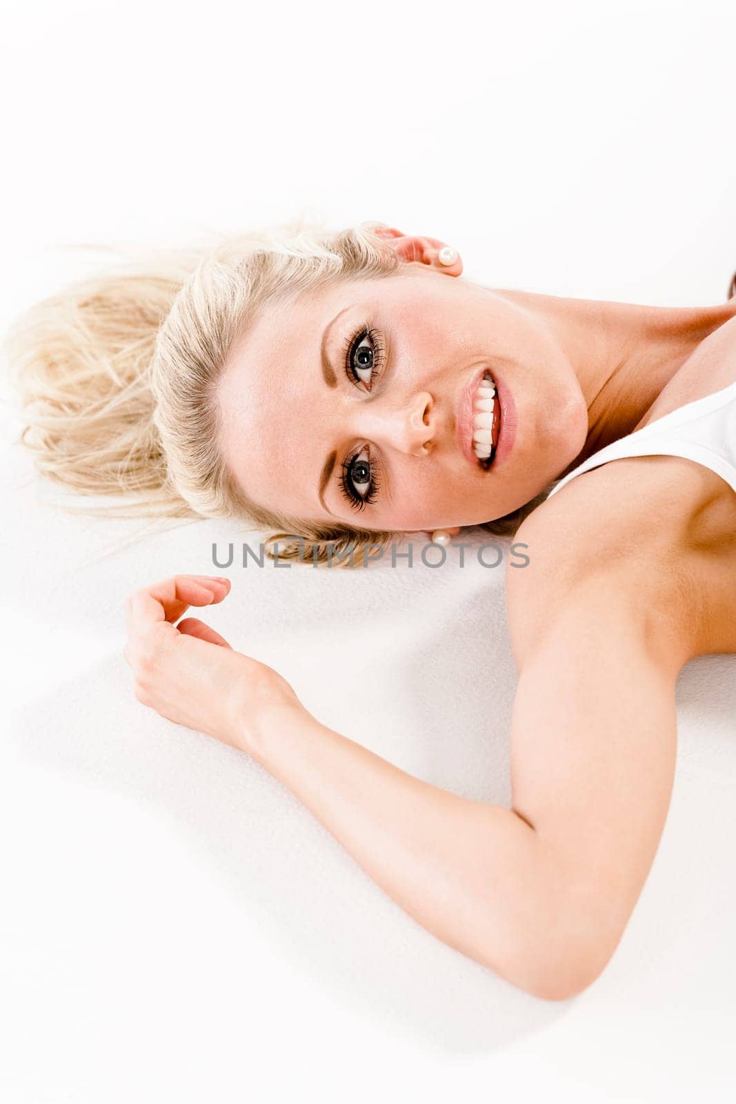 Attractive young woman in a white vest top sitting on the floor on white background