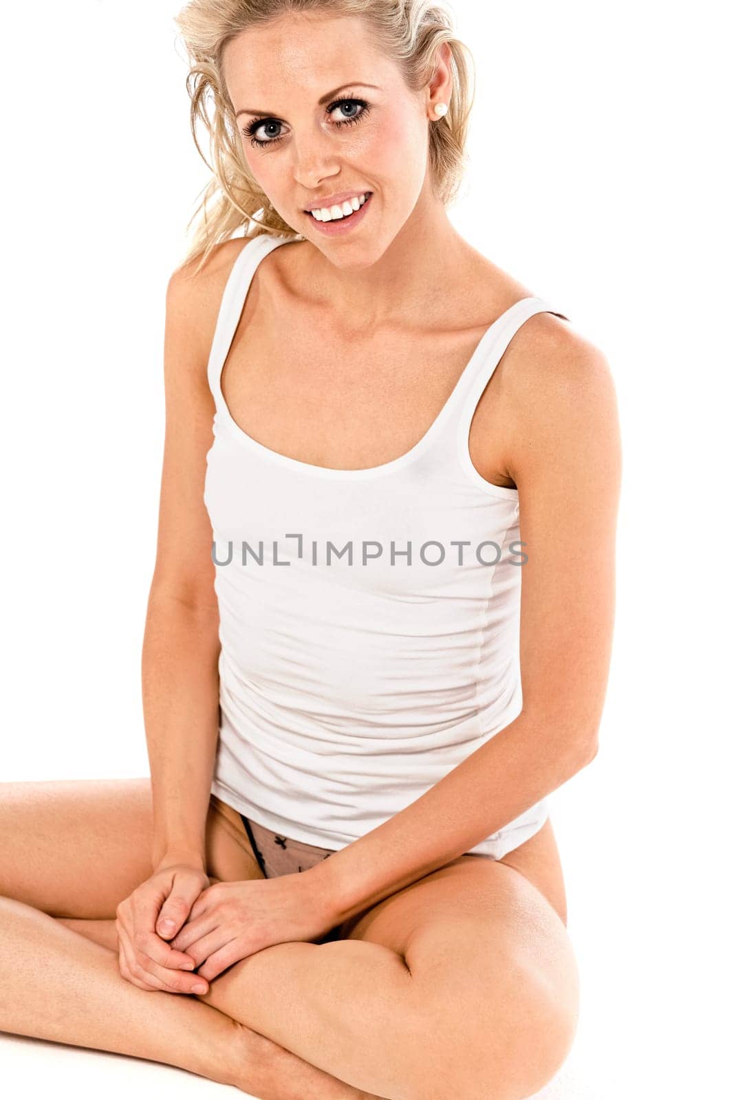 Attractive young woman in a white vest top sitting on the floor on white background