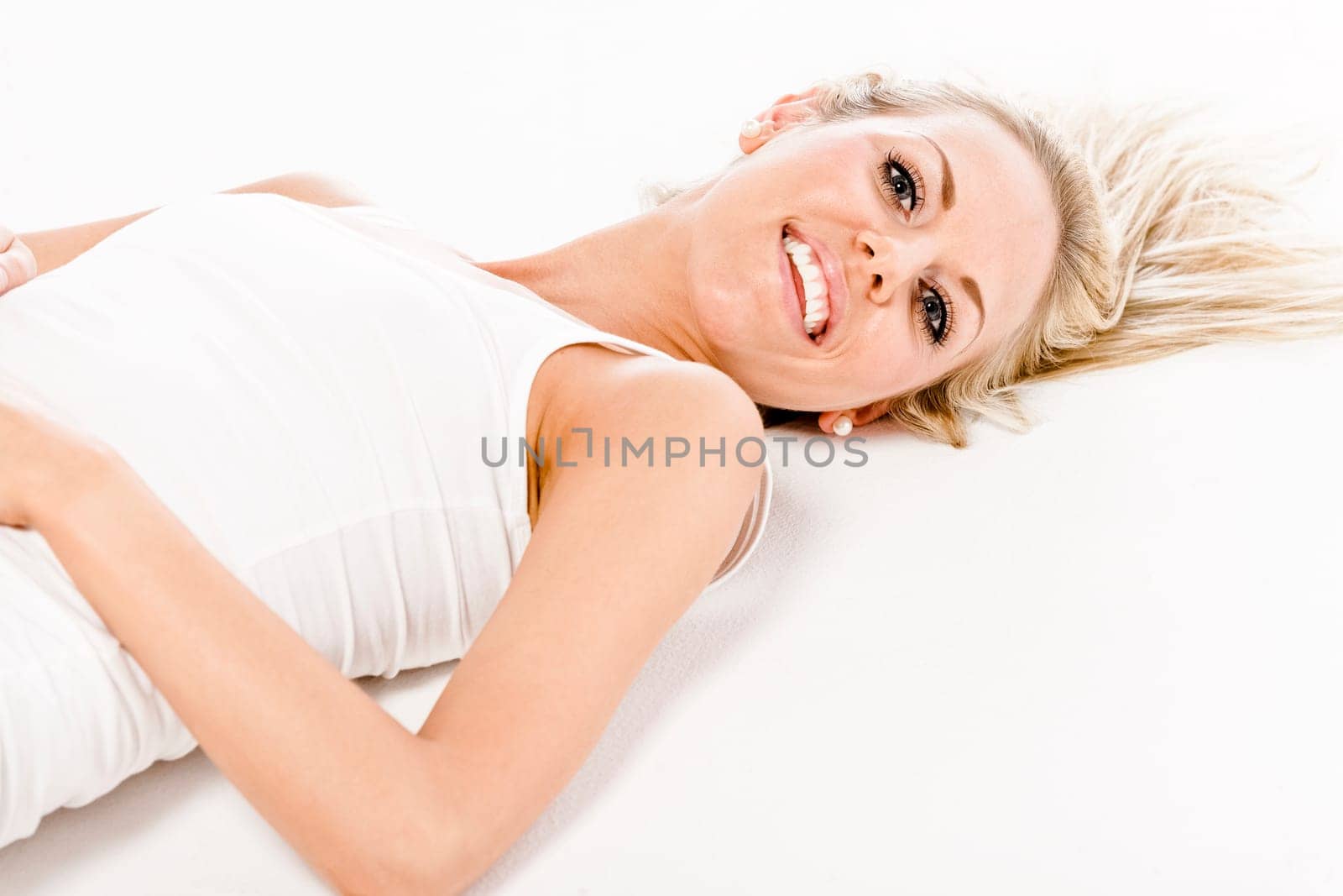 Attractive young woman in a white vest top sitting on the floor on white background
