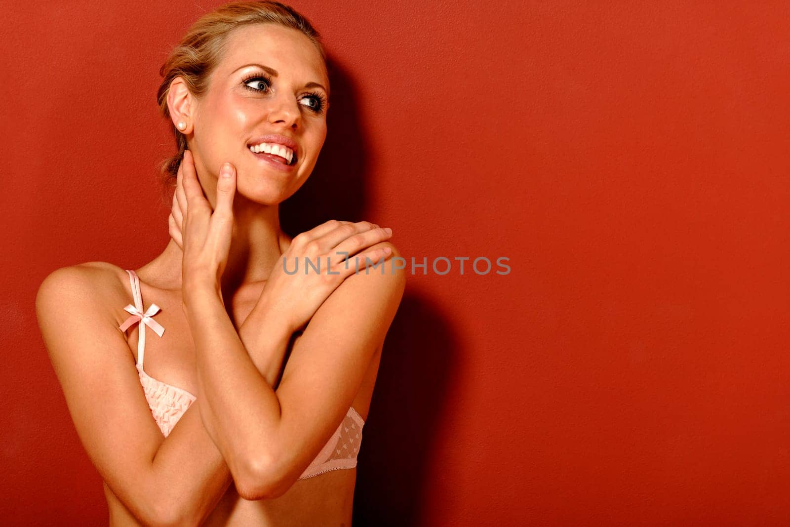 beautiful young woman wearing underwear while sitting on the floor against a red wall