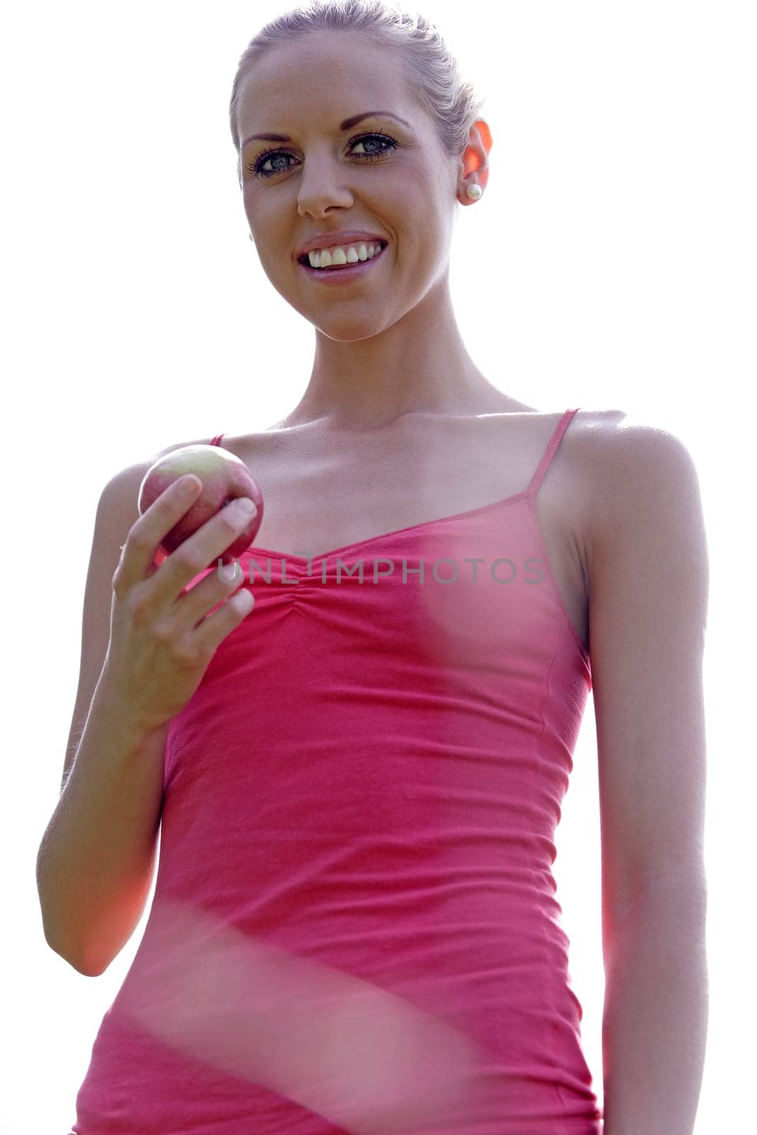 Beautiful young woman eating an apple on a summers day in the countryside.