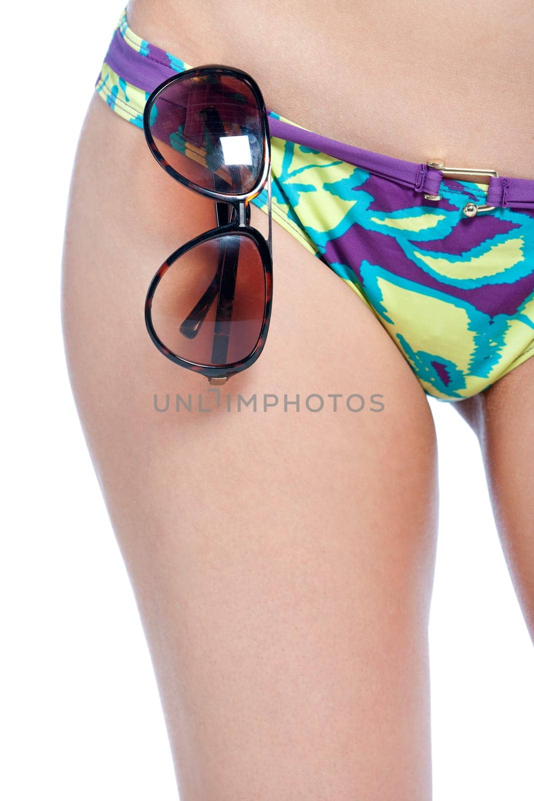 Cropped image of a womans hips showing a bikini bottom with sunglasses