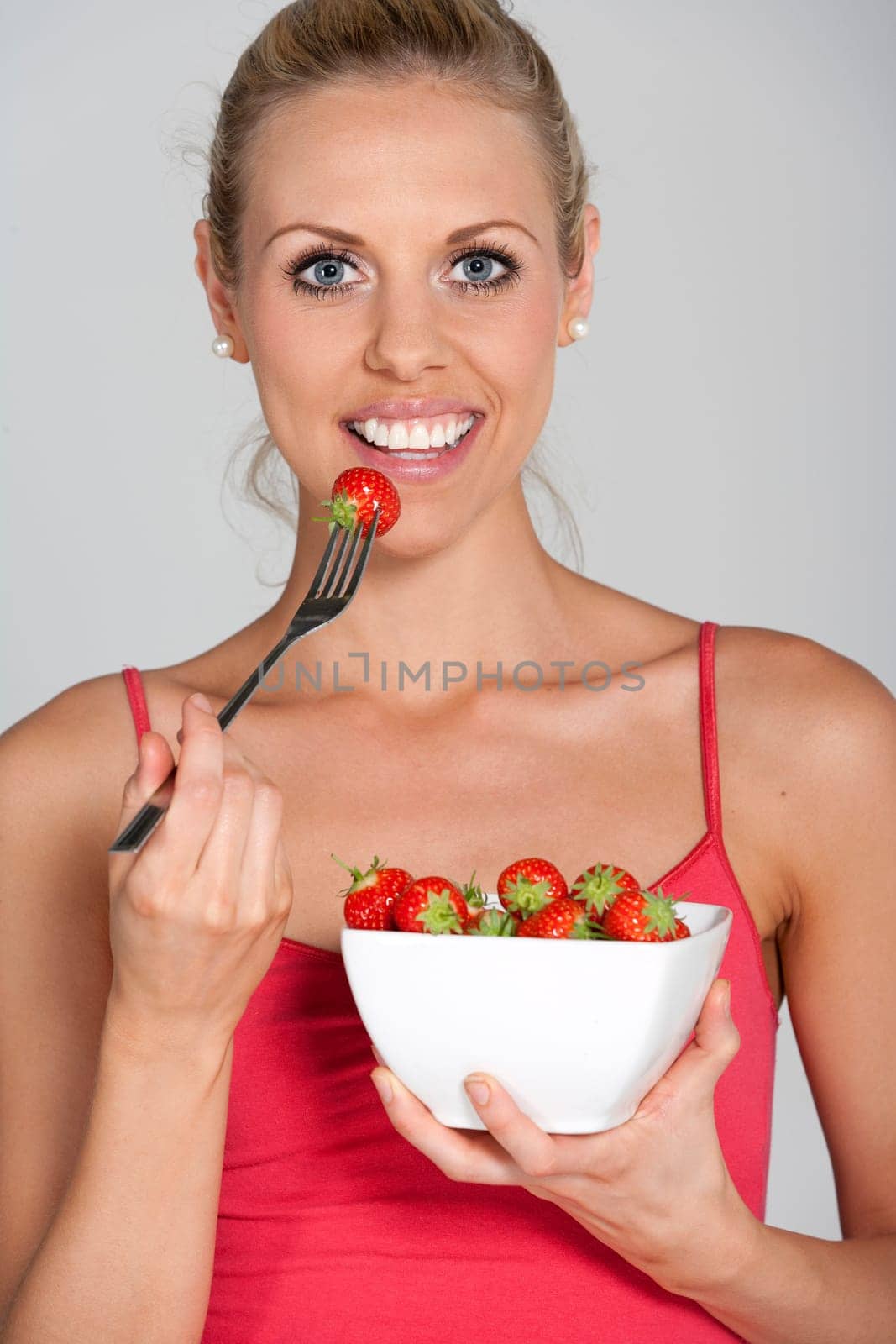 Beautiful young woman eating fresh summer berries