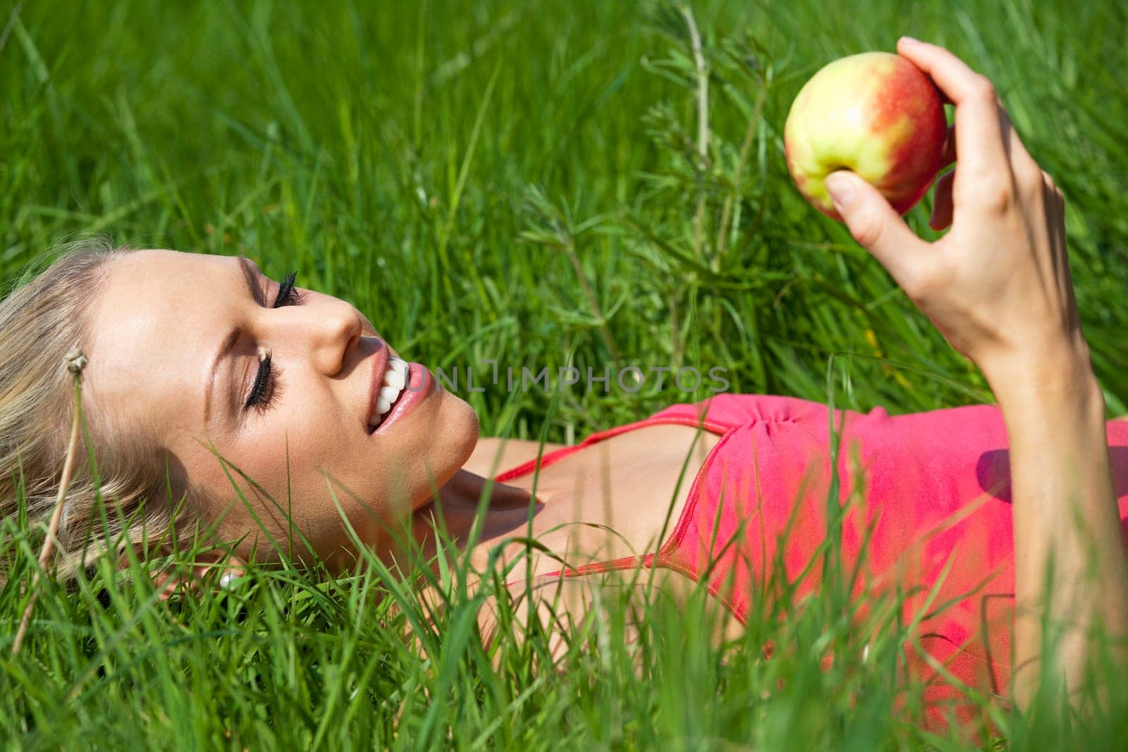 Beautiful young woman eating an apple on a summers day in the countryside.