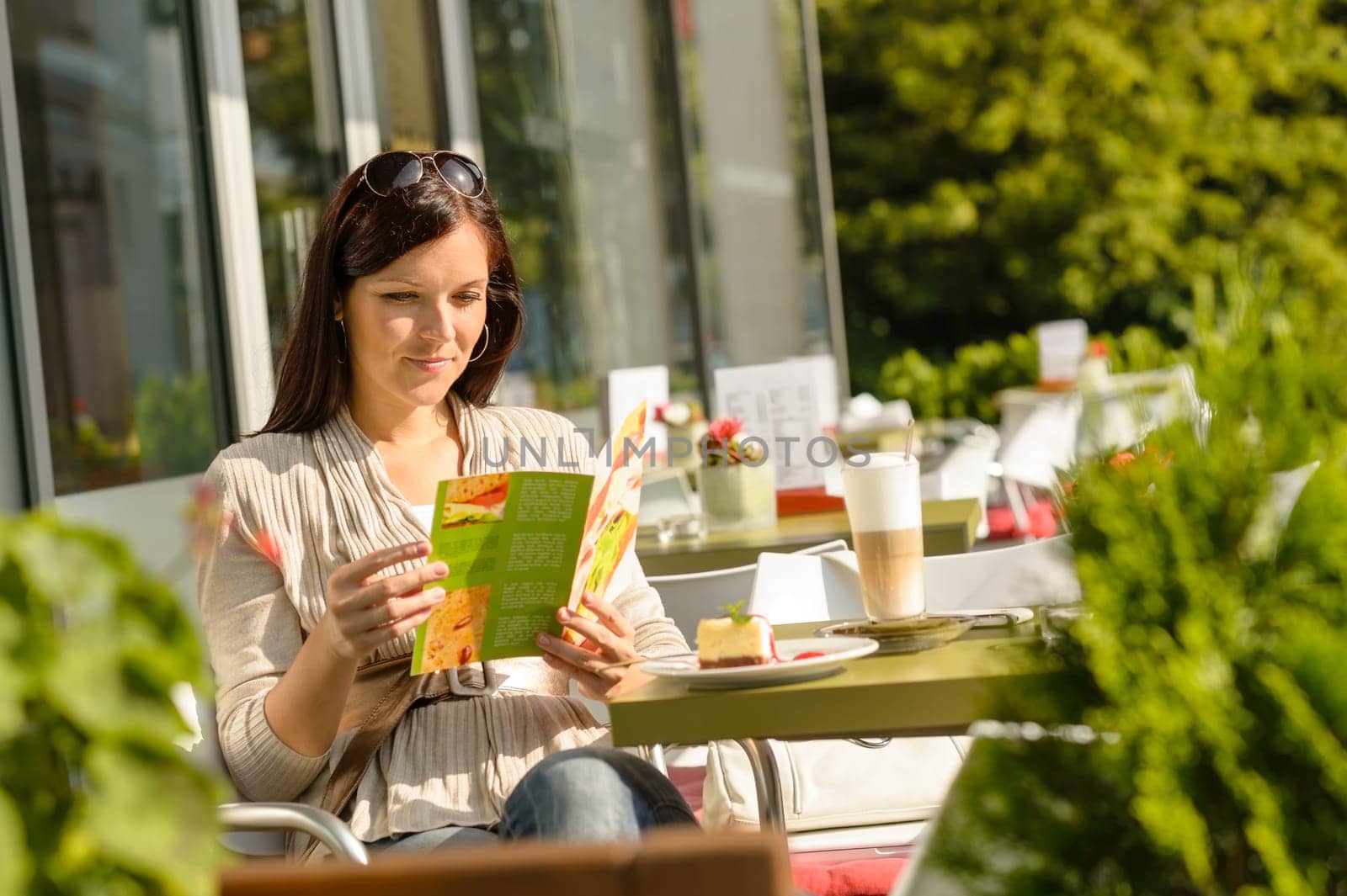 Woman looking at menu sitting cafe bar terrace choice dessert