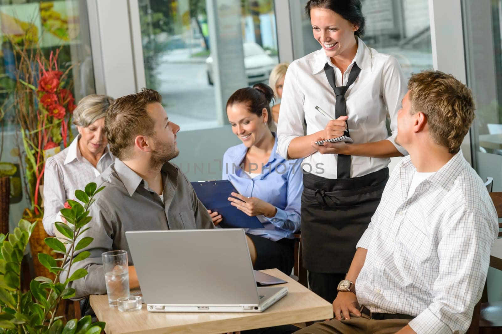 Waitress taking order from businessmen in cafe smiling laptop work