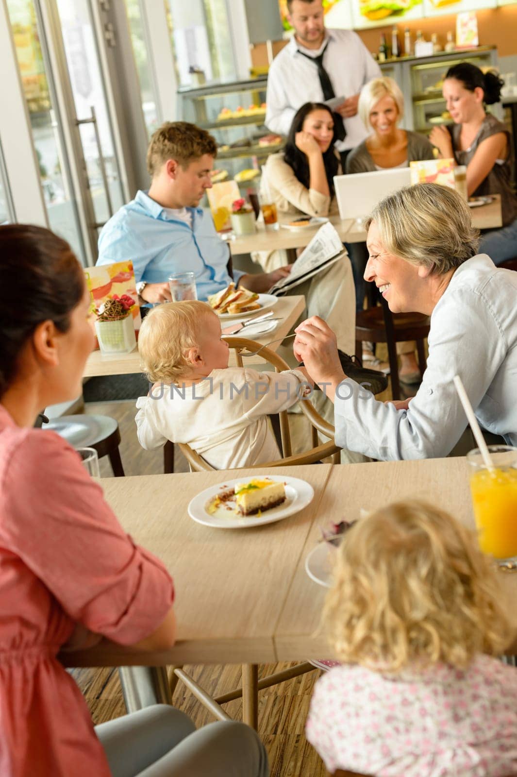 Mother and grandmother with children at cafe eating cake women