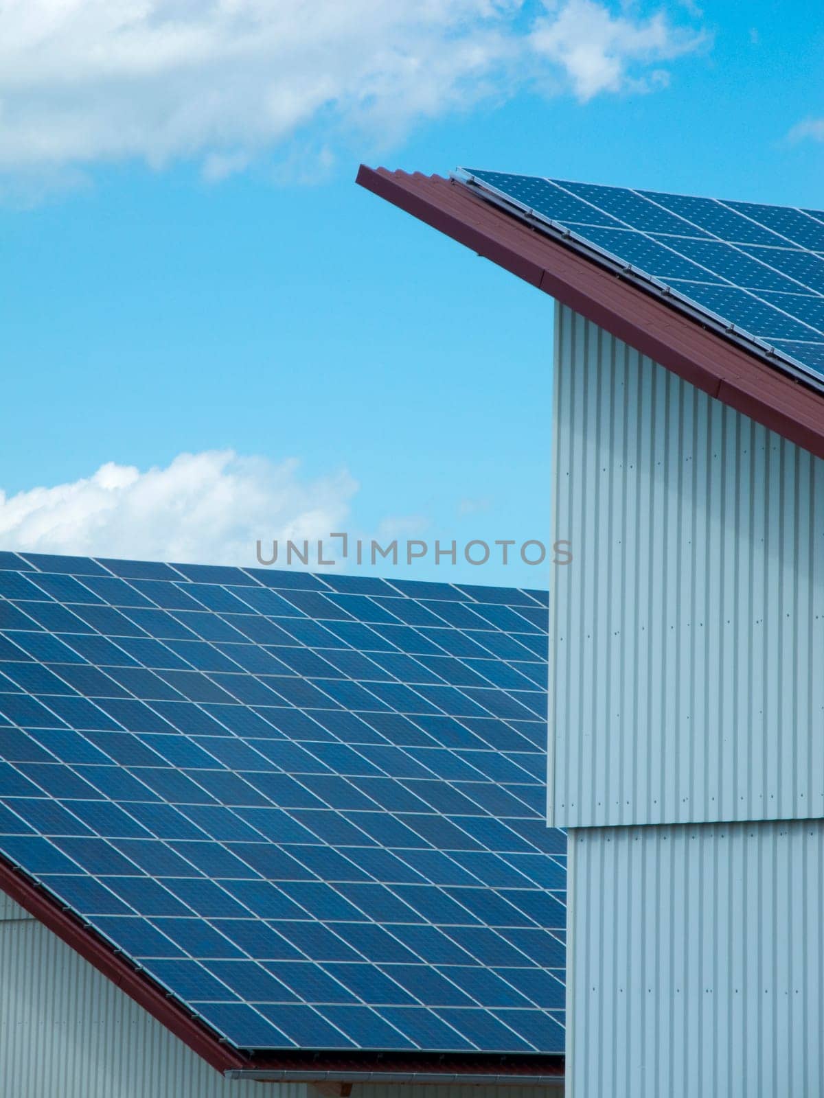 Side view of a warehouse with photovoltaic system on the entire roof under blue sky with white clouds