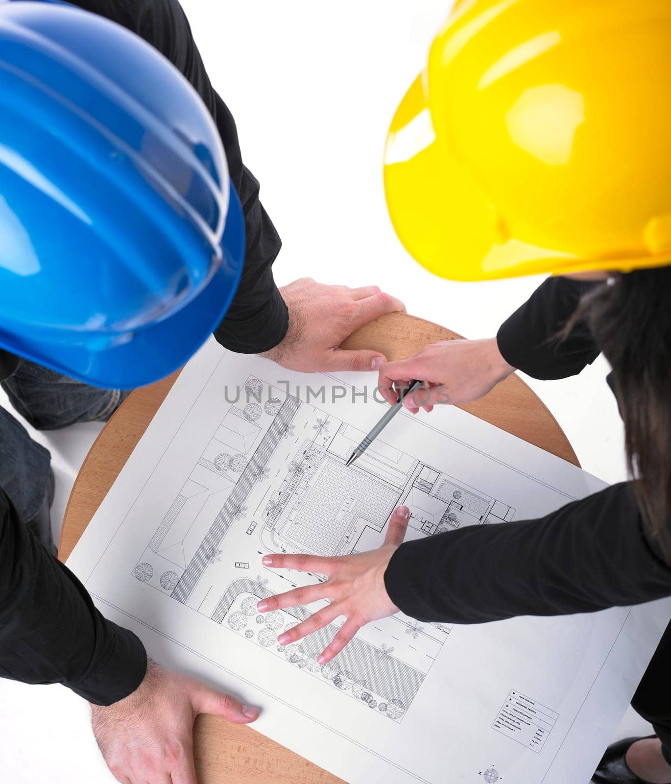 Two architects with hard hats and plan on meeting in office