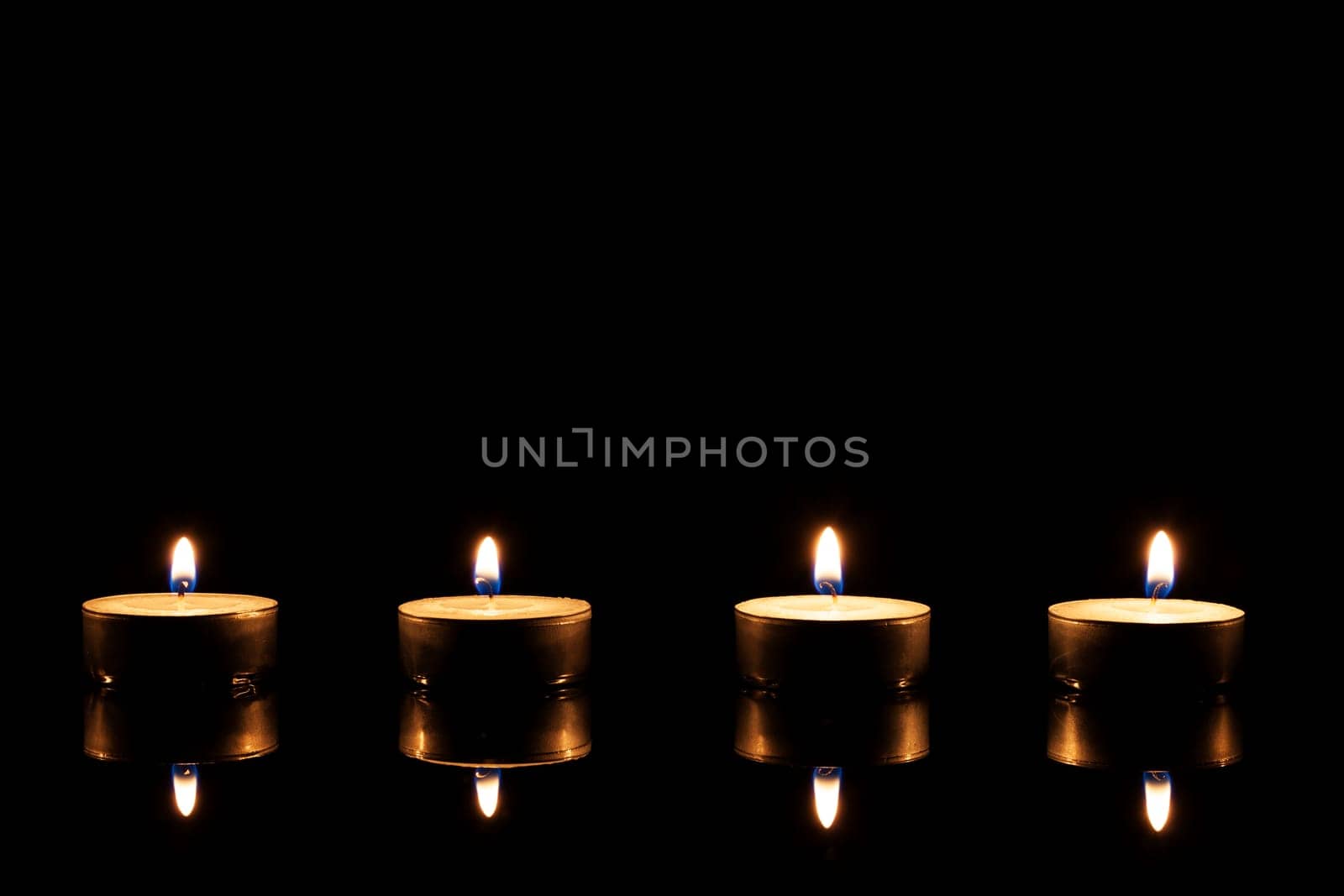Four tea lights against black background