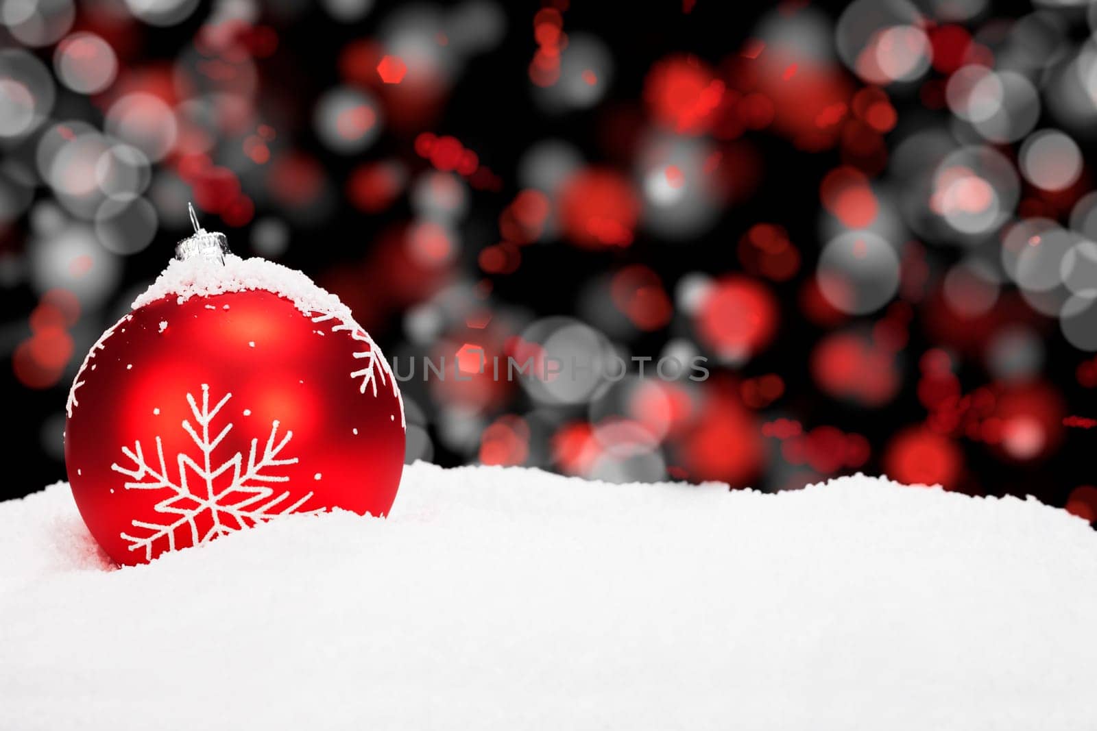 Red Christmas tree ball in the snow in front of red white light