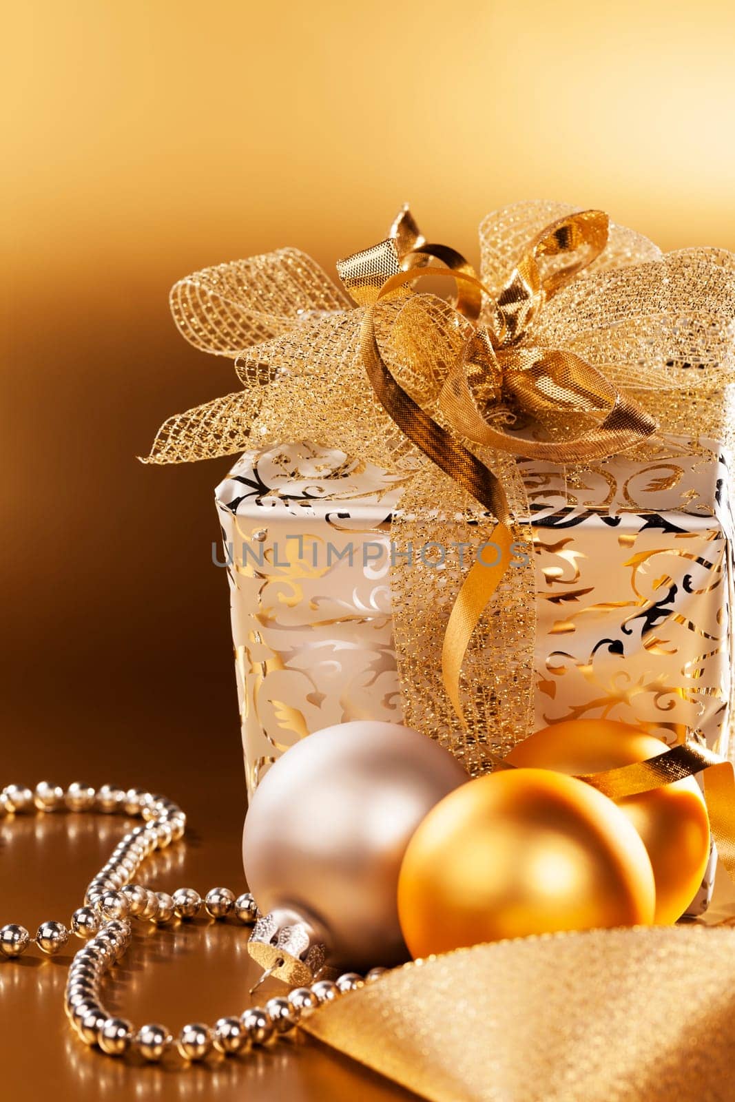 Christmas gift with baubles in front of golden background