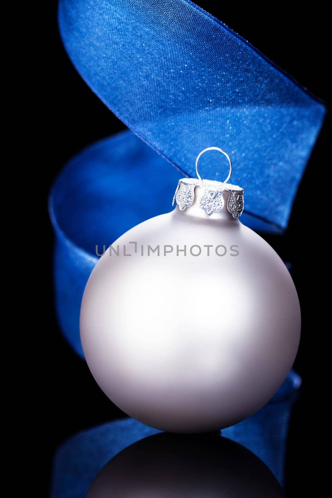 Silver Christmas Ornament with Blue Fabric Ribbon in Front of Black