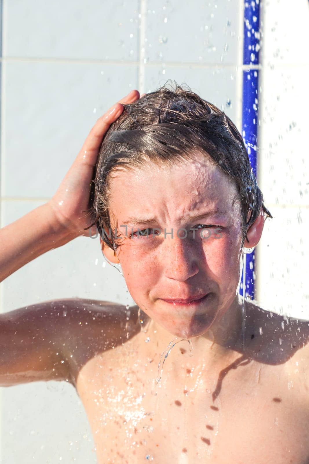 cute boy has fun unter the pool shower