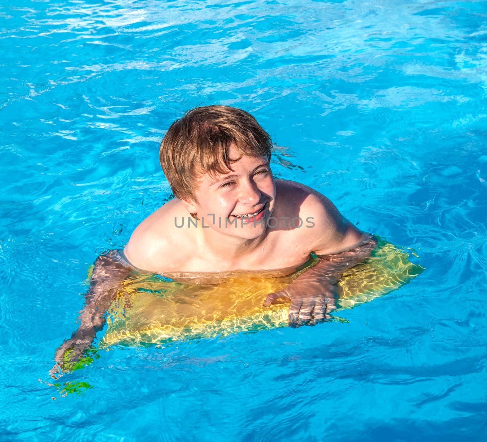 cute boy relaxing on a surfboard in the pool