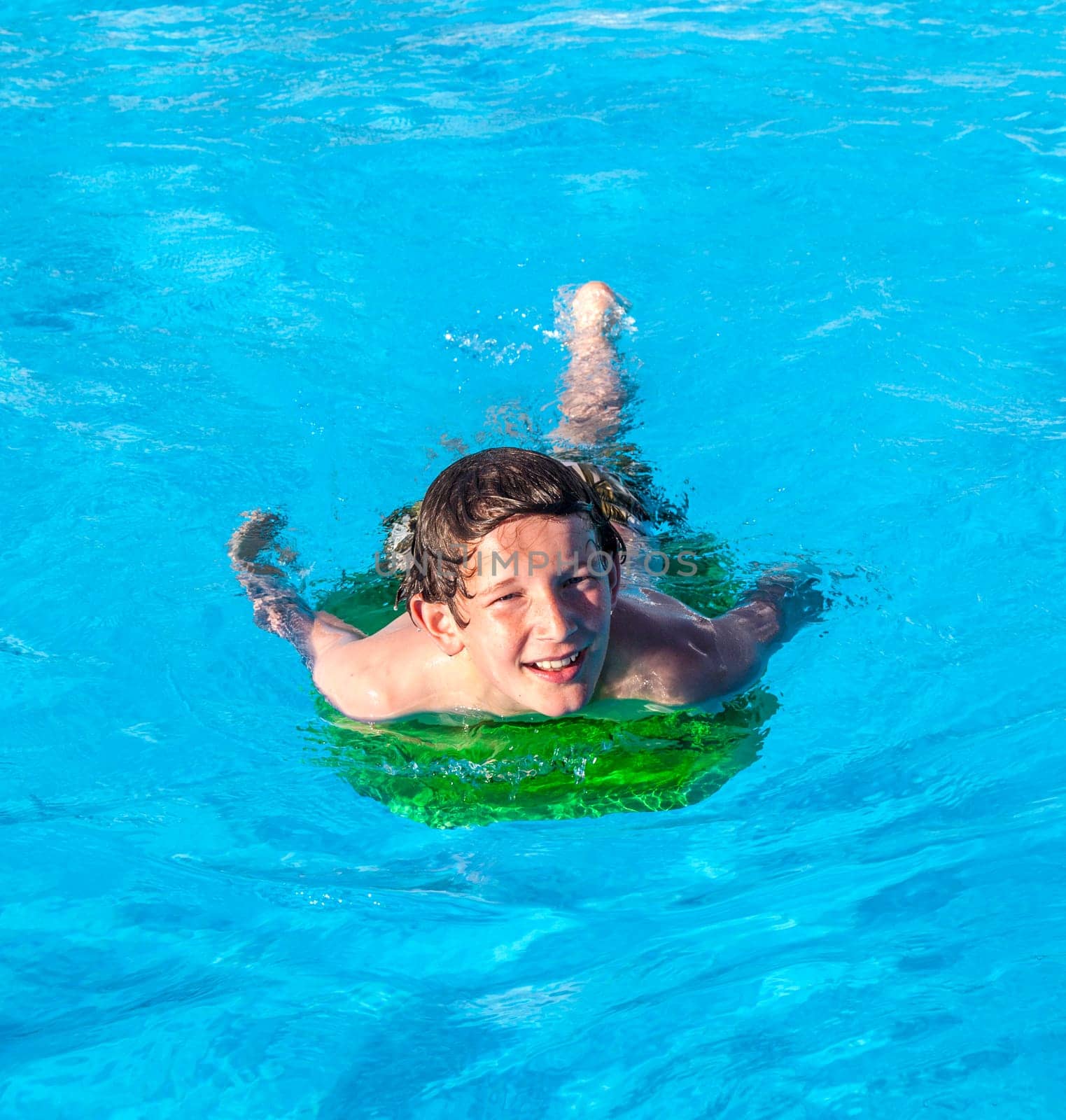 cute boy relaxing on a surfboard in the pool