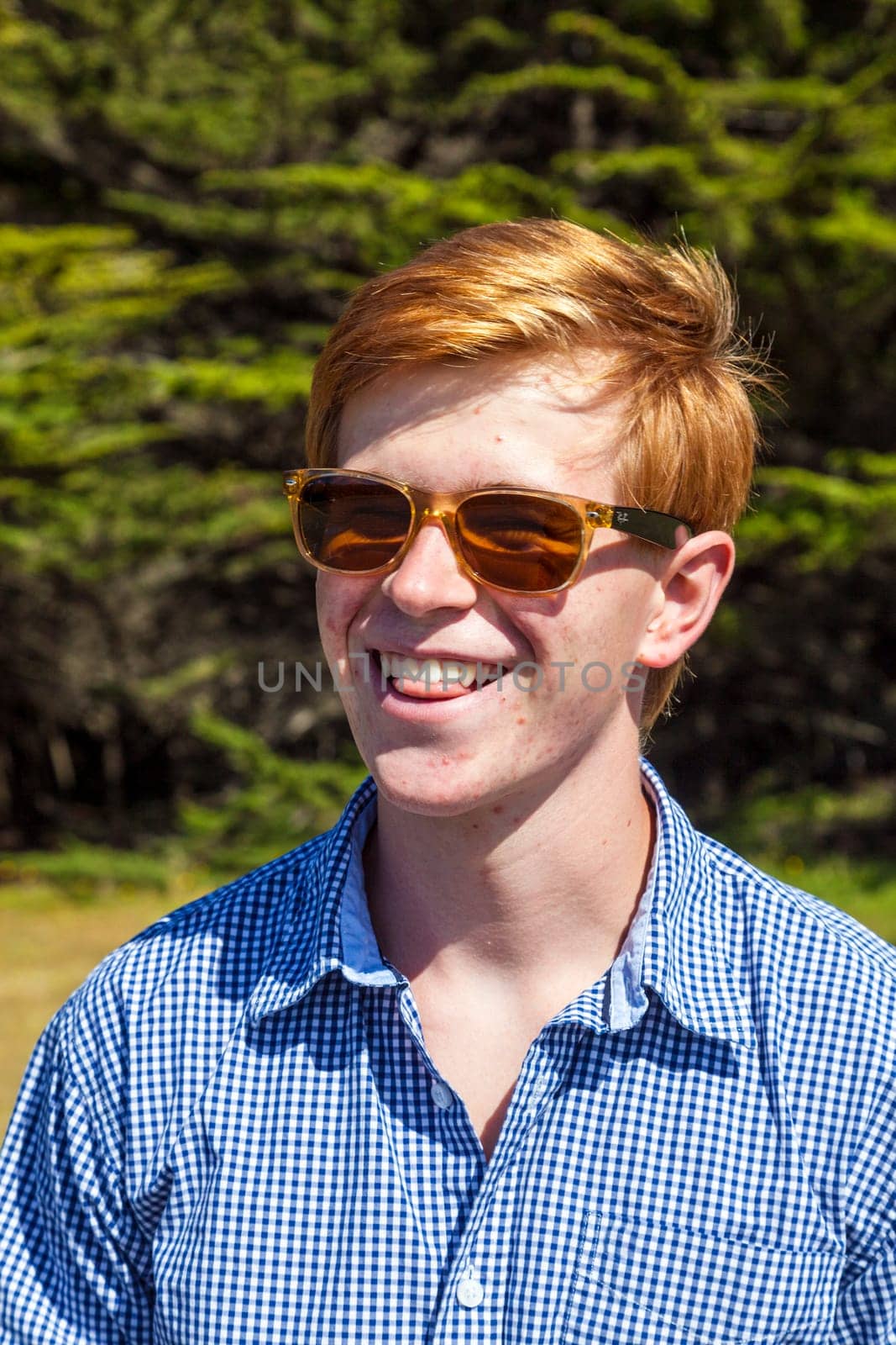 cool teenage boy with sunglasses walks happy on the meadow