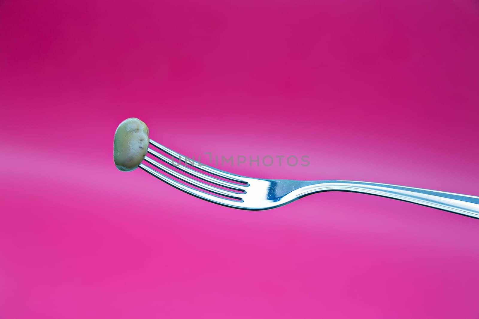 Green bean on metal chromed fork on background