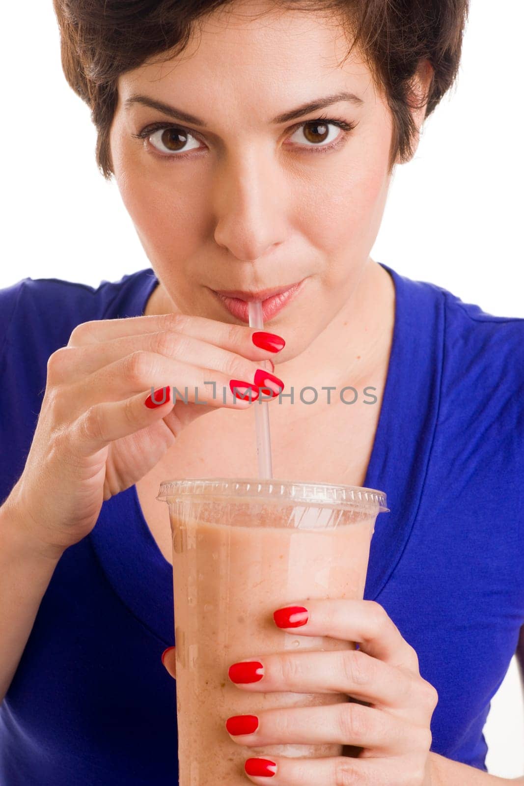 Beautiful woman with manicured nails sips a green smoothie