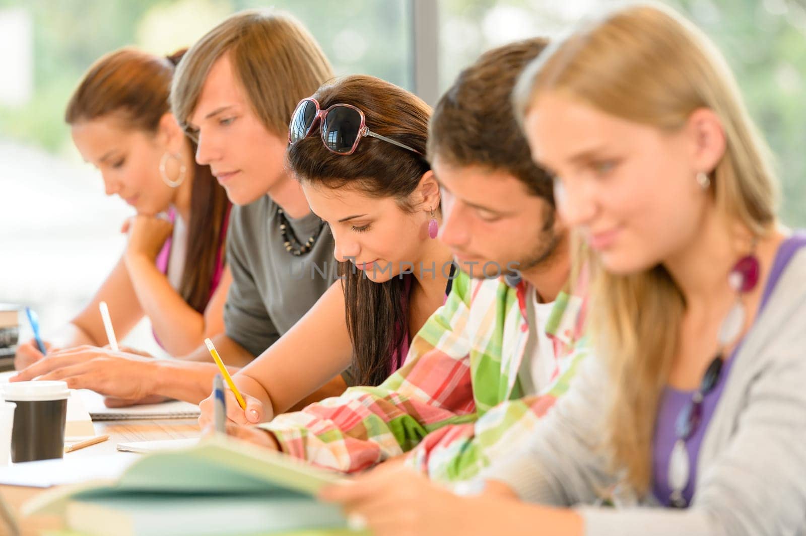 Students writing at high-school exam teens study campus academic class