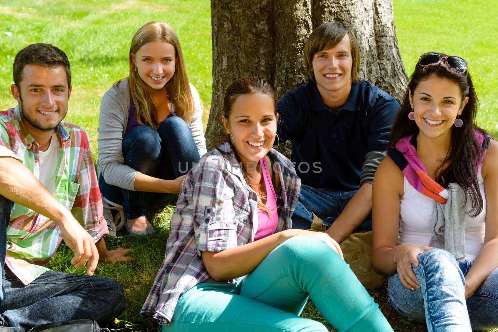 Students relaxing on meadow in park teens happy group leisure