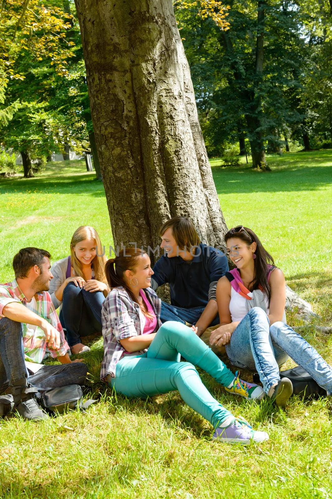 Students sitting in park talking smiling teens leisure campus schoolyard