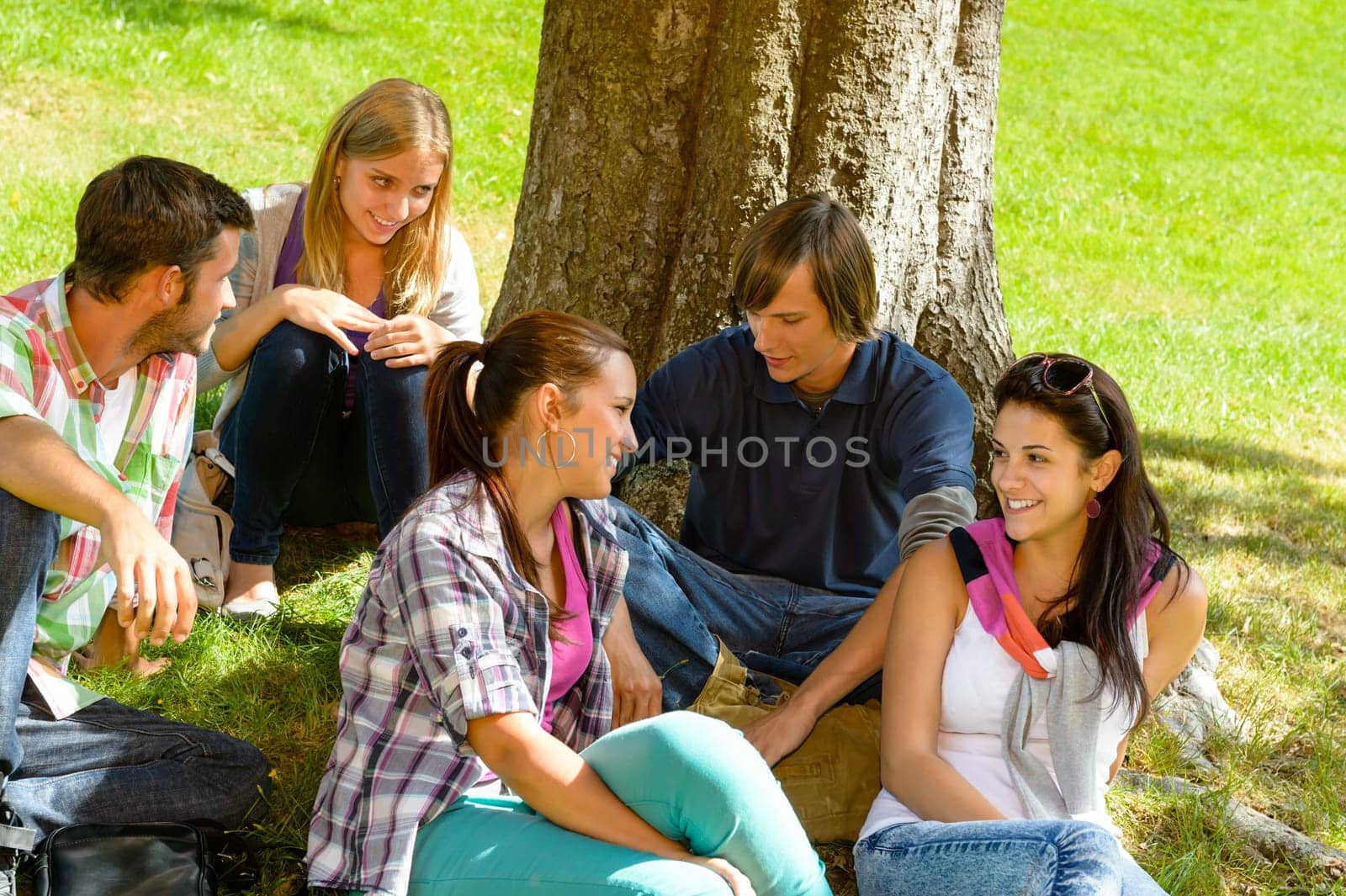 Students sitting in park talking smiling teens leisure campus schoolyard
