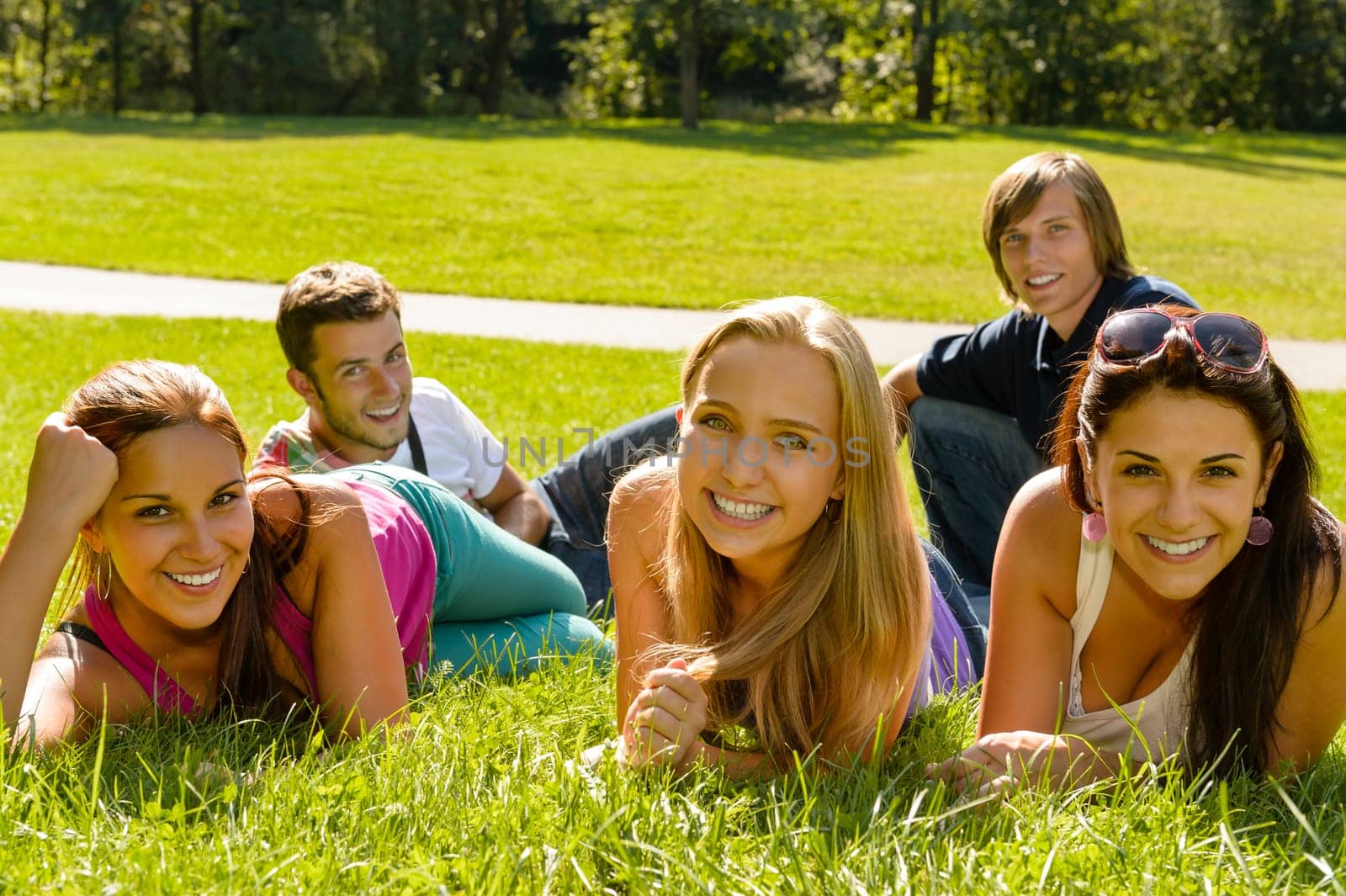 Students laying on grass in park campus smiling relaxing happy