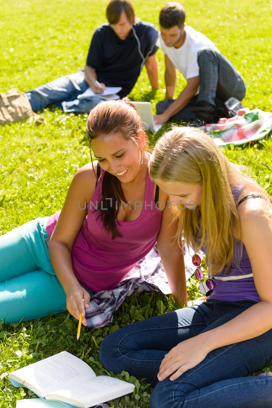 Teens studying in park reading book students happy campus research