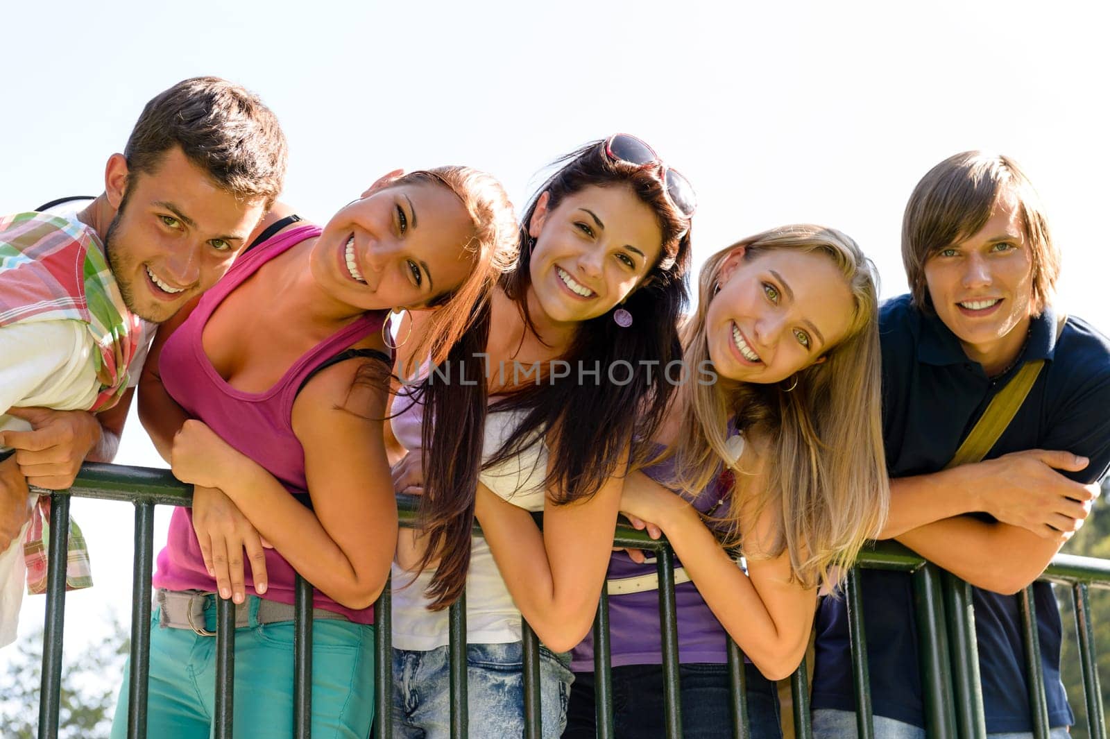 Teens having fun in park leaning fence happy students relaxing