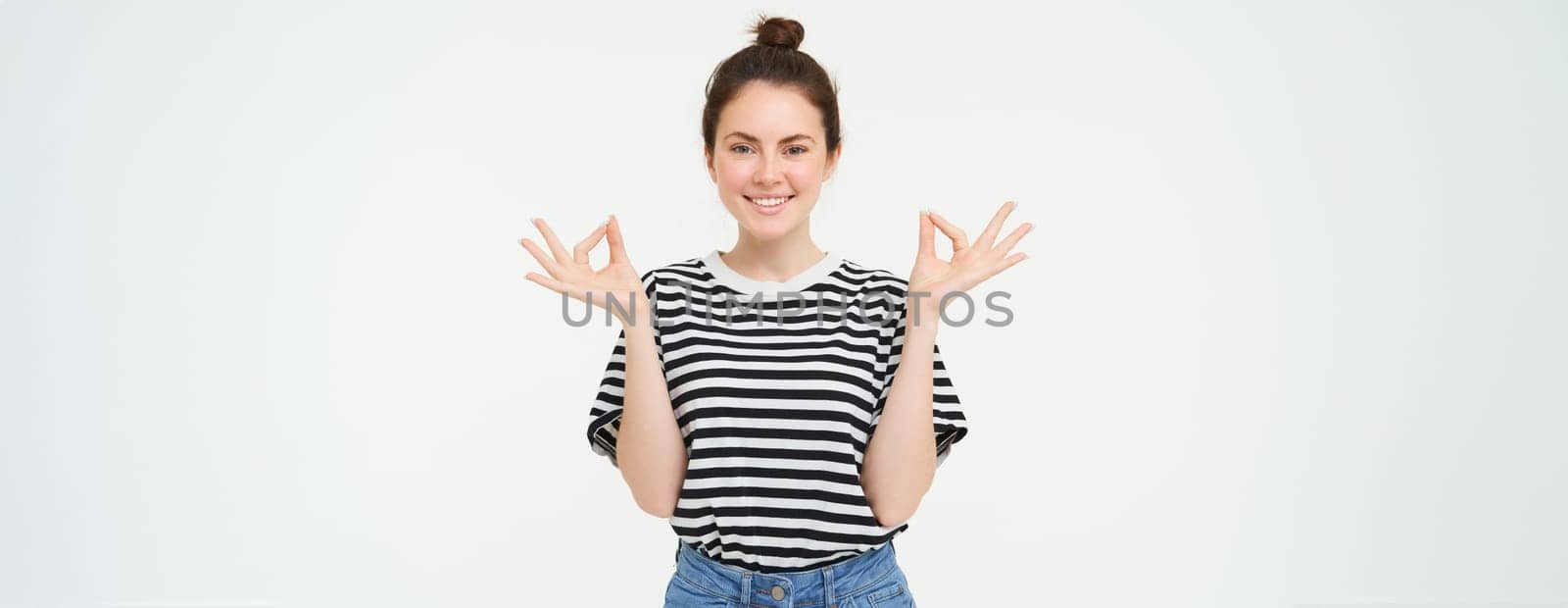 Keep calm and meditate. Young woman relaxing, standing in asana, zen pose, holding hands sideways and meditating, standing over white background by Benzoix