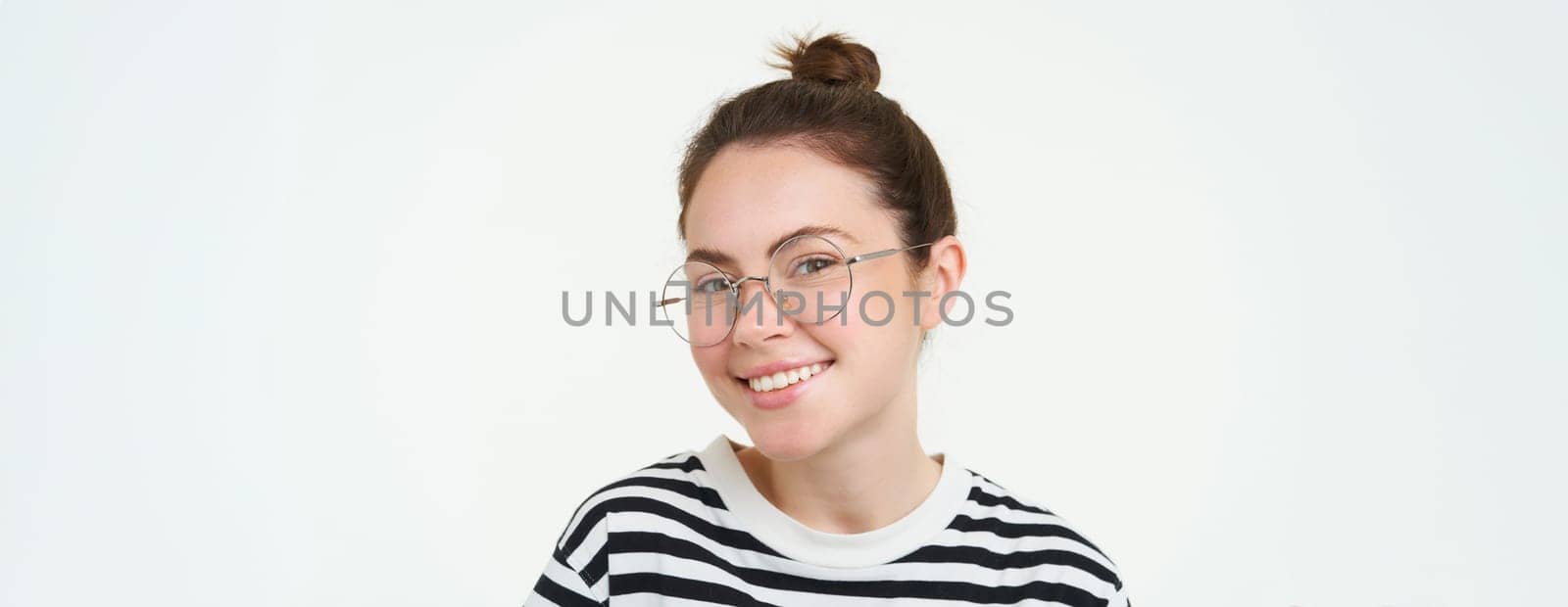 Image of young woman in glasses, using her mobile phone, standing with smartphone and smiling, standing over white background.