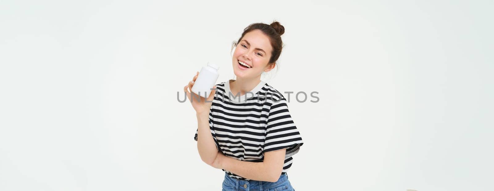 Healthcare and wellbeing. Young woman holding bottle with vitamins, dietary supplements, treatment for good skin and hair, standing over white background.