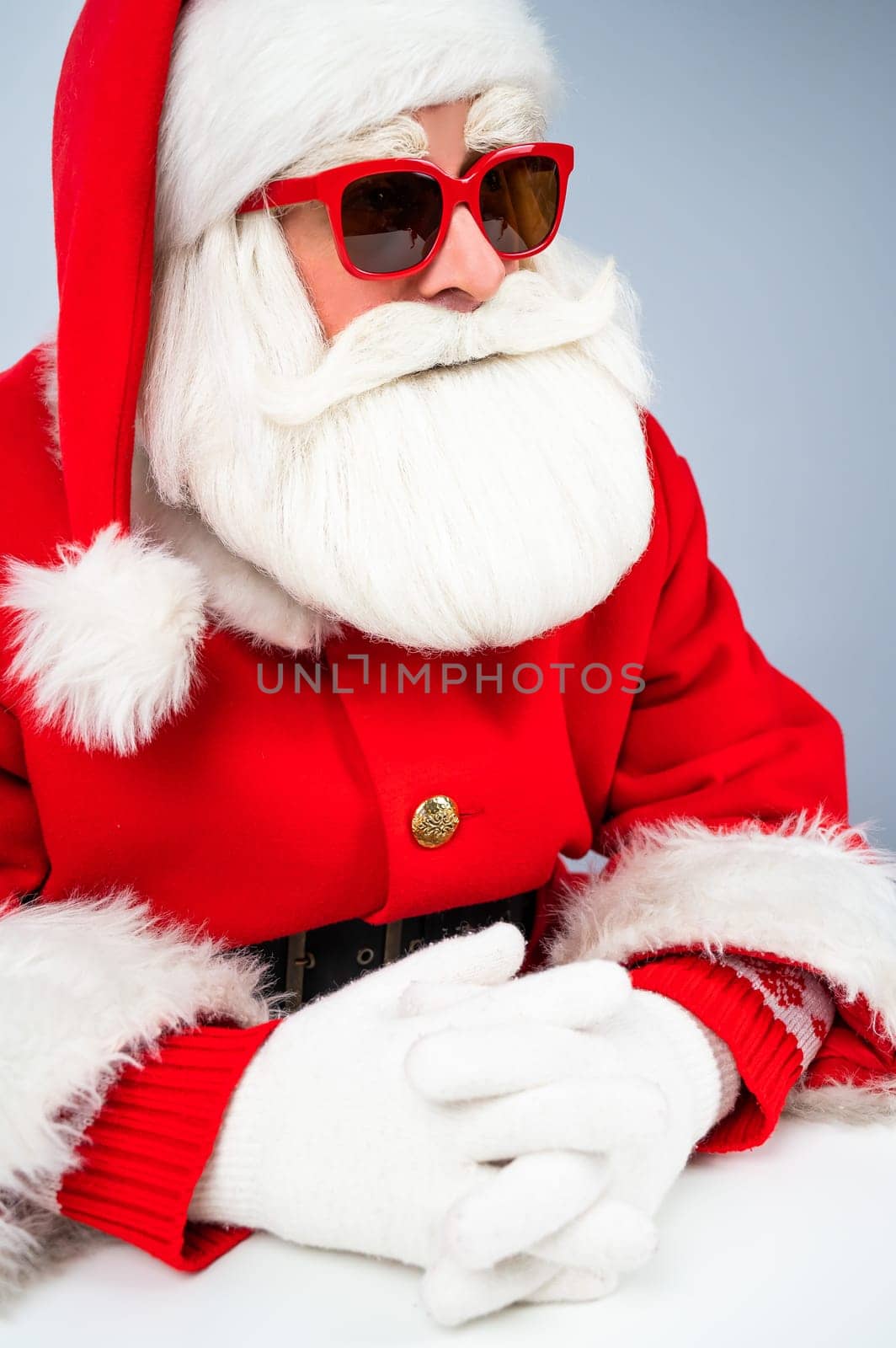 Portrait of santa claus sitting with his arms folded at a white table