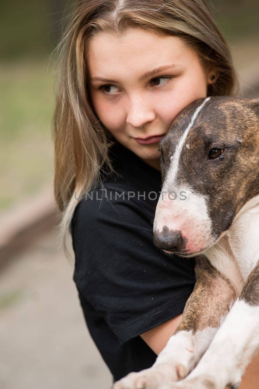 Portrait of caucasian woman hugging her bull terrier dog outdoors