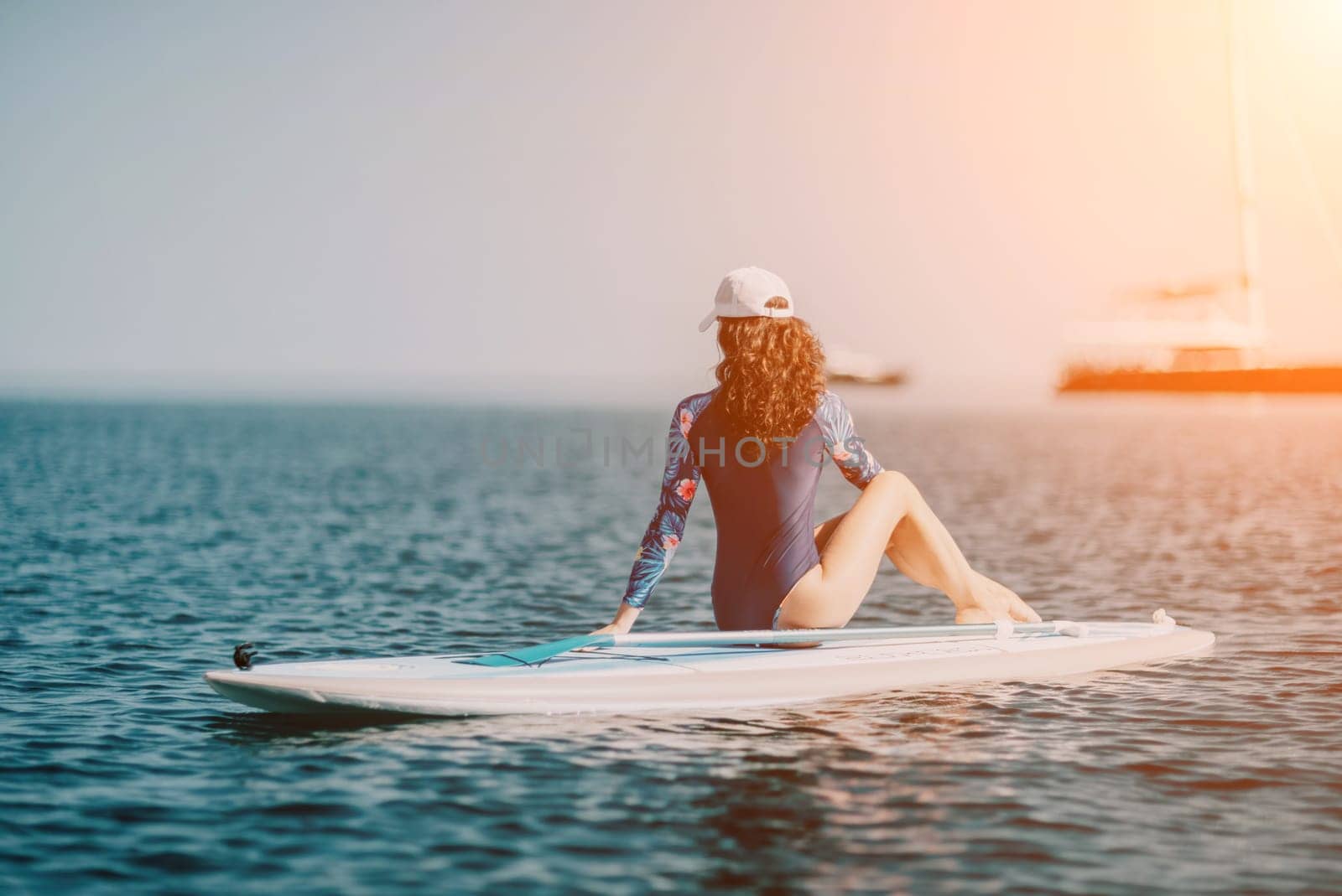 Woman sup yoga. Middle age sporty woman practising yoga pilates on paddle sup surfboard. Female stretching doing workout on sea water. Modern individual hipster outdoor summer sport activity